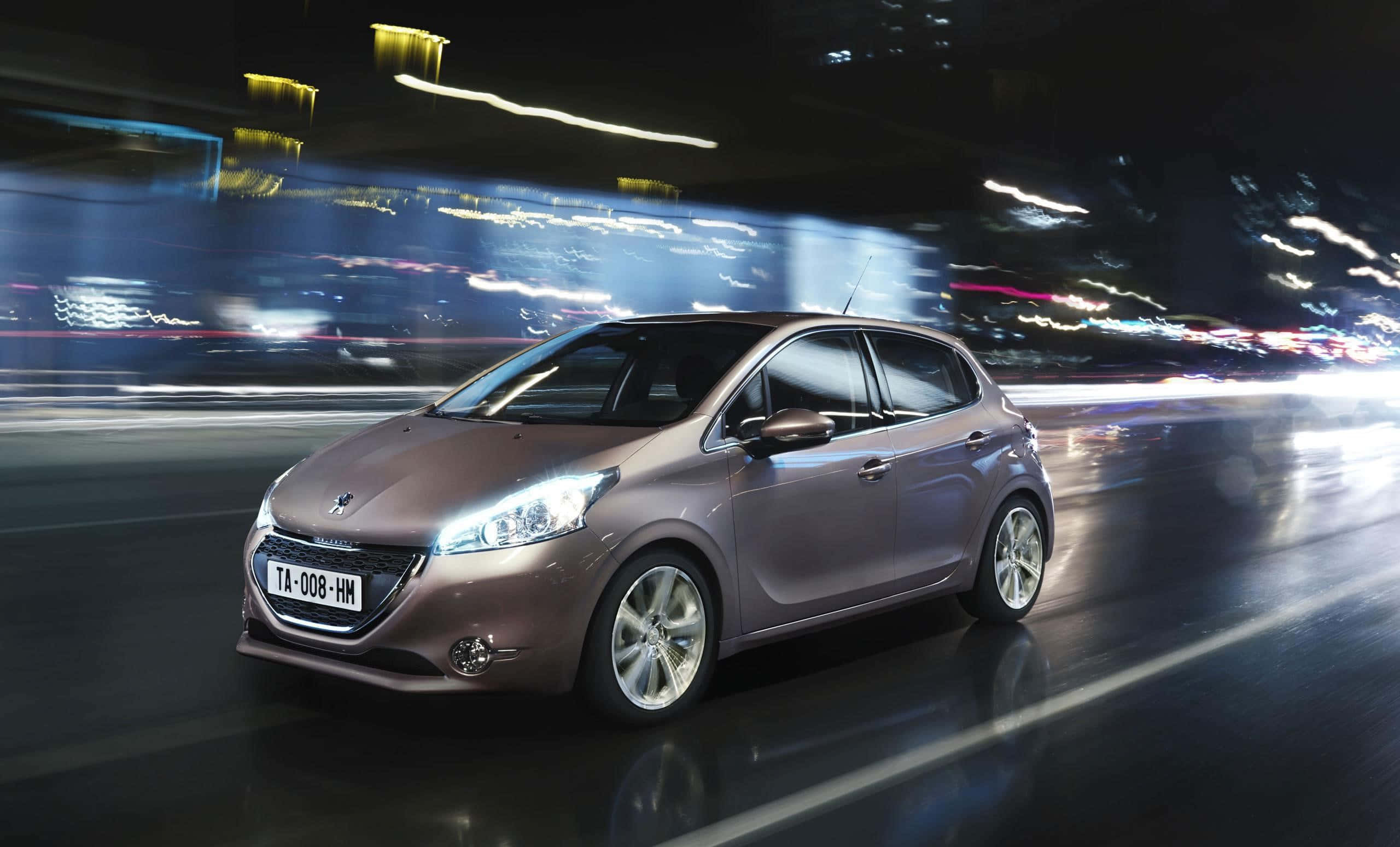Peugeot 208 桌布 壁紙 — 一輛時尚的青銅色掀背車在霓虹燈閃爍的夜間城市中飛馳，背景燈光形成模糊的線條。
