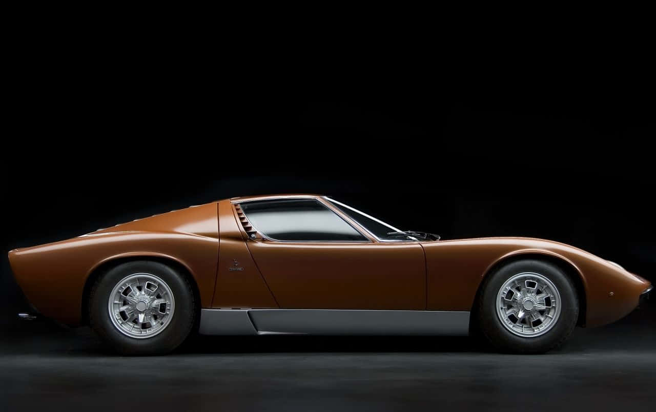 Lamborghini Miura 桌布 壁紙 — 一輛流線型青銅色林寶堅尼Miura跑車，以側面輪廓展示在黑色攝影棚背景前。