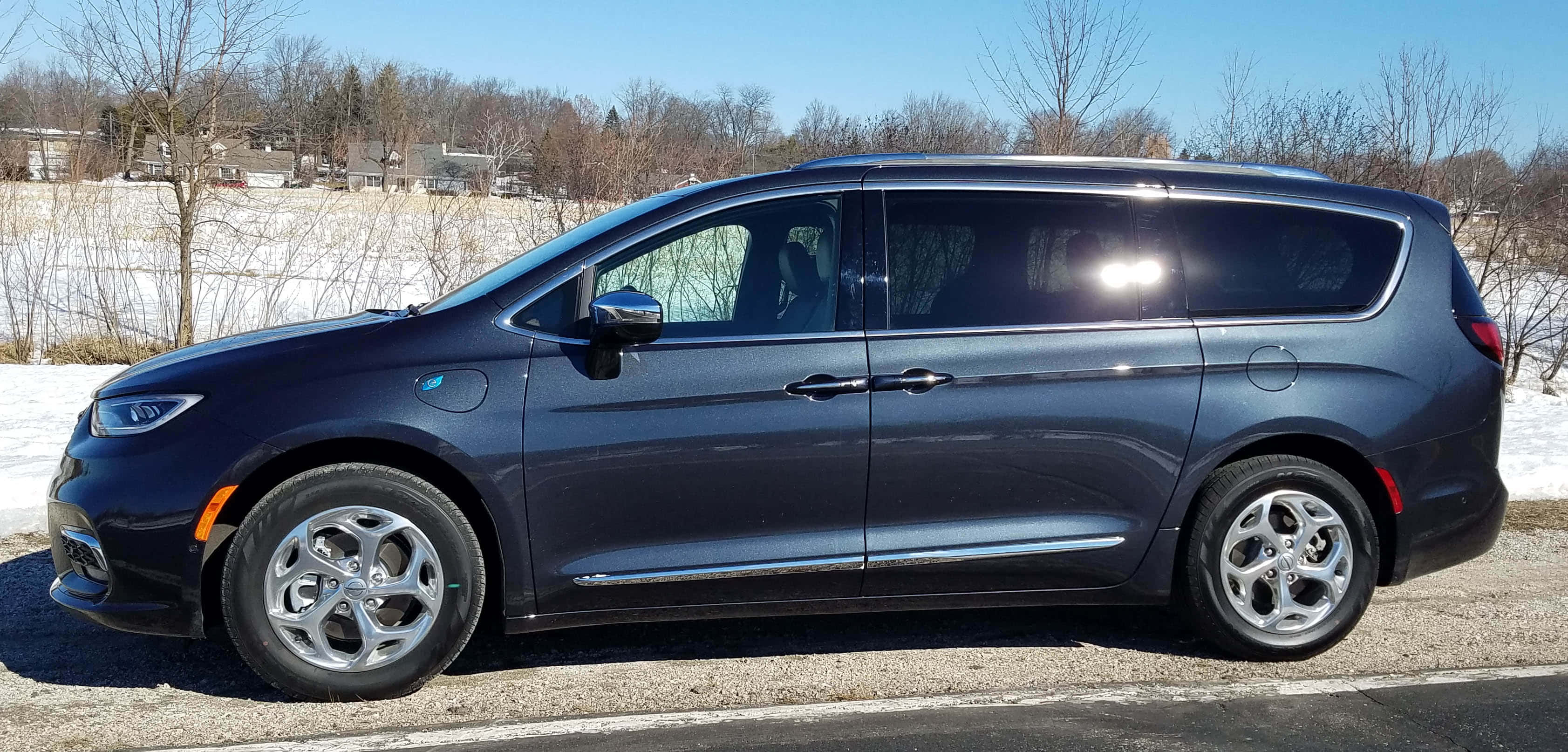 Chrysler Pacifica 桌布 壁紙 — 一架時尚深藍色小型貨車停泊在碎石路上，旁邊是白雪覆蓋的田野，上方是晴朗的藍天。