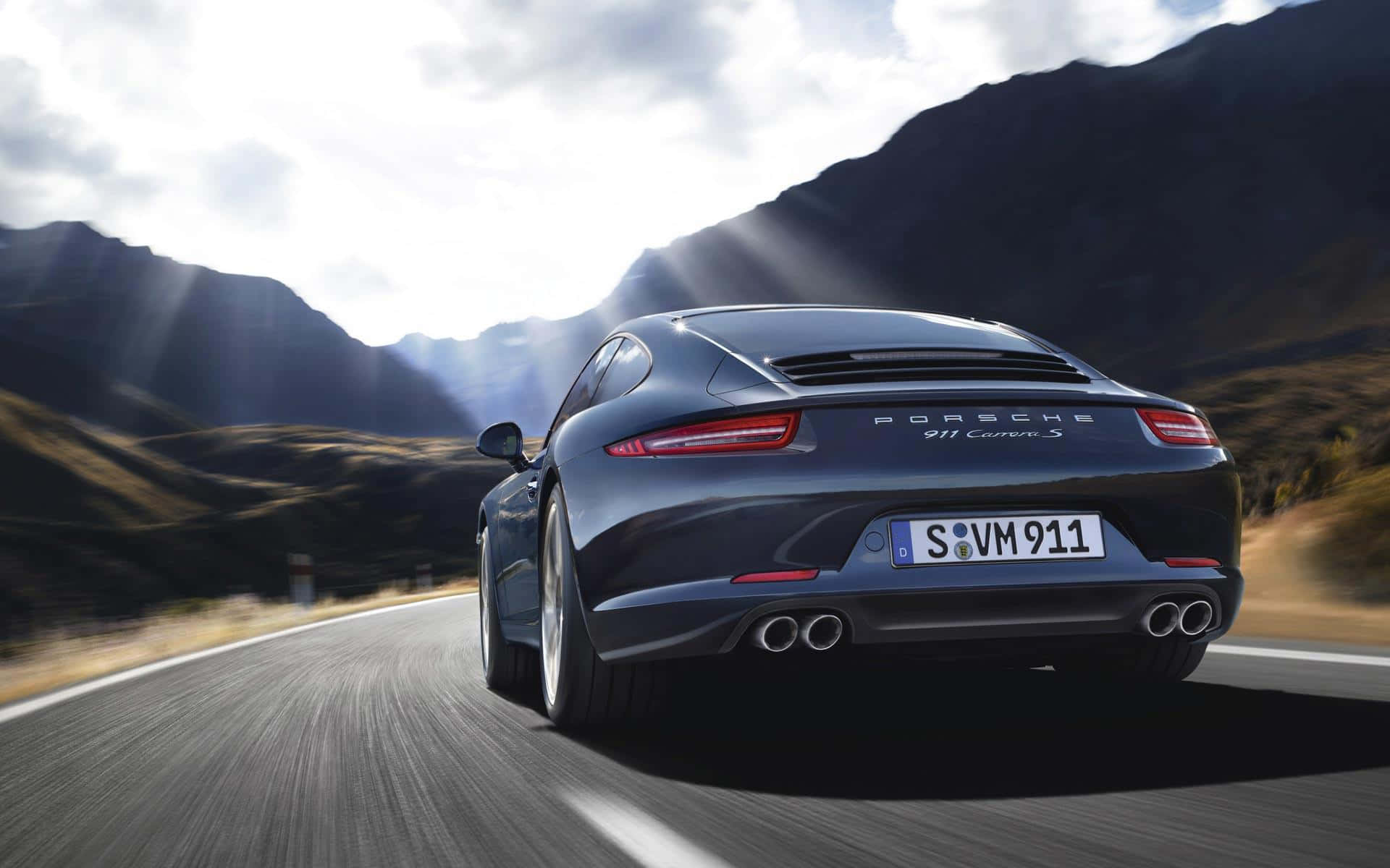 深藍色保時捷911 Carrera S在日落時分的山路上疾馳。