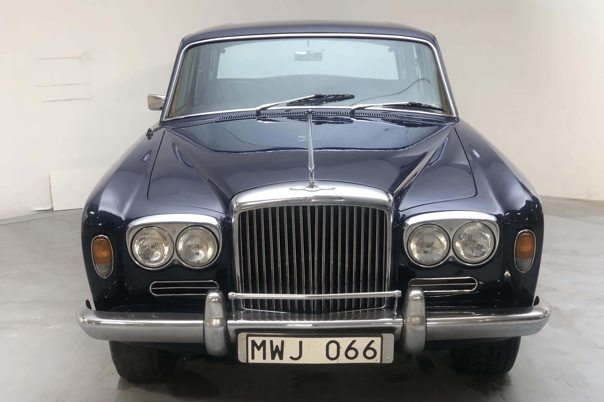 Bentley T1 桌布 壁紙 — 一輛時尚的深藍色復古賓利，帶有鍍鉻格柵和圓形頭燈，在簡約的白色工作室中正面朝前。
