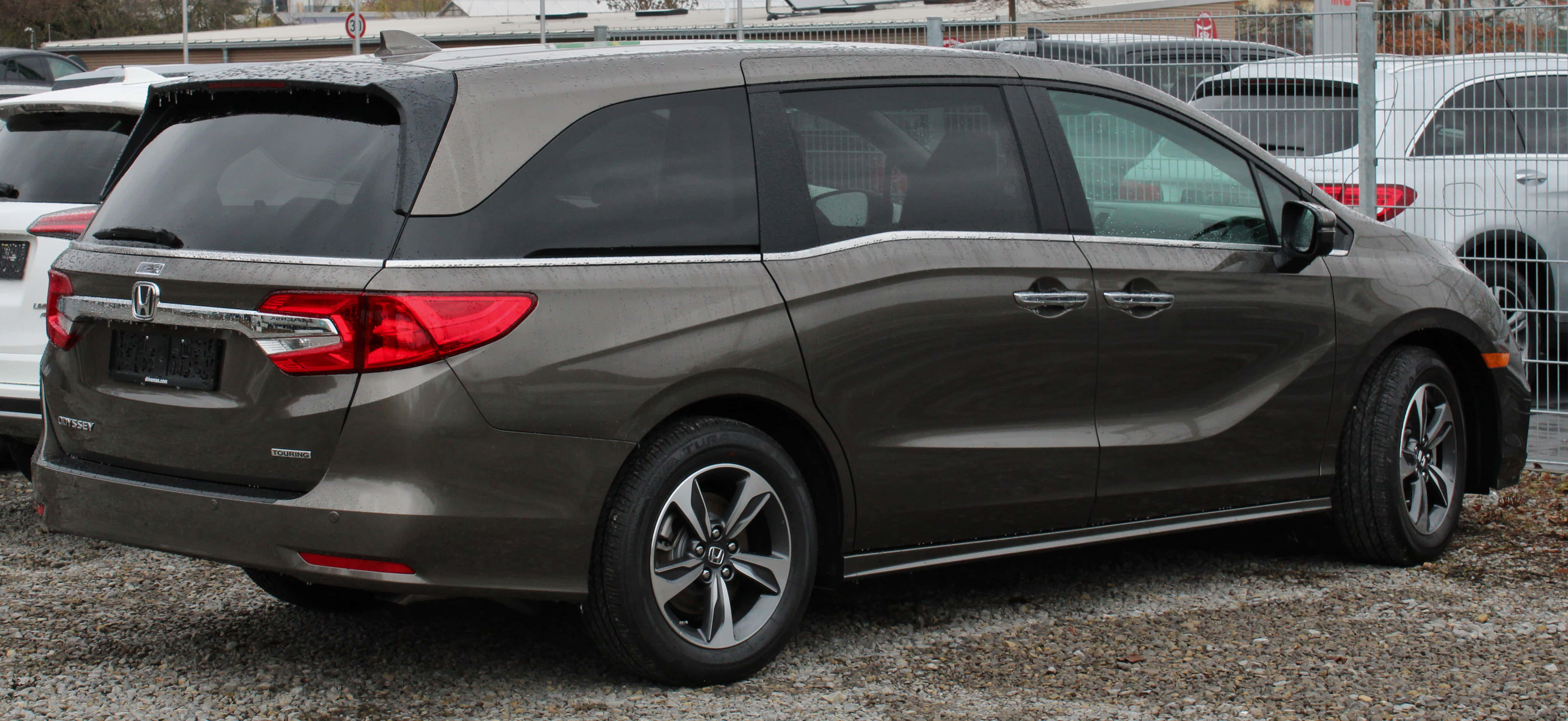 Honda Odyssey 桌布 壁紙 — 一輛時尚的深灰色本田奧德賽小型貨車停在礫石上，帶有紅色尾燈和銀色合金輪圈。