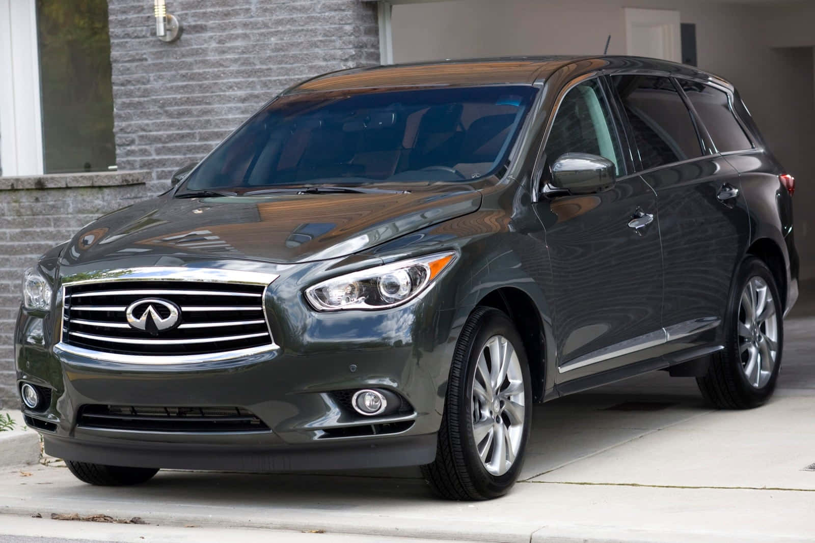 Infiniti Jx35 桌布 壁紙 — 一輛時尚的深灰色 Infiniti QX60 SUV 停泊在磚屋旁邊的混凝土車道上，磚屋擁有現代化外牆。