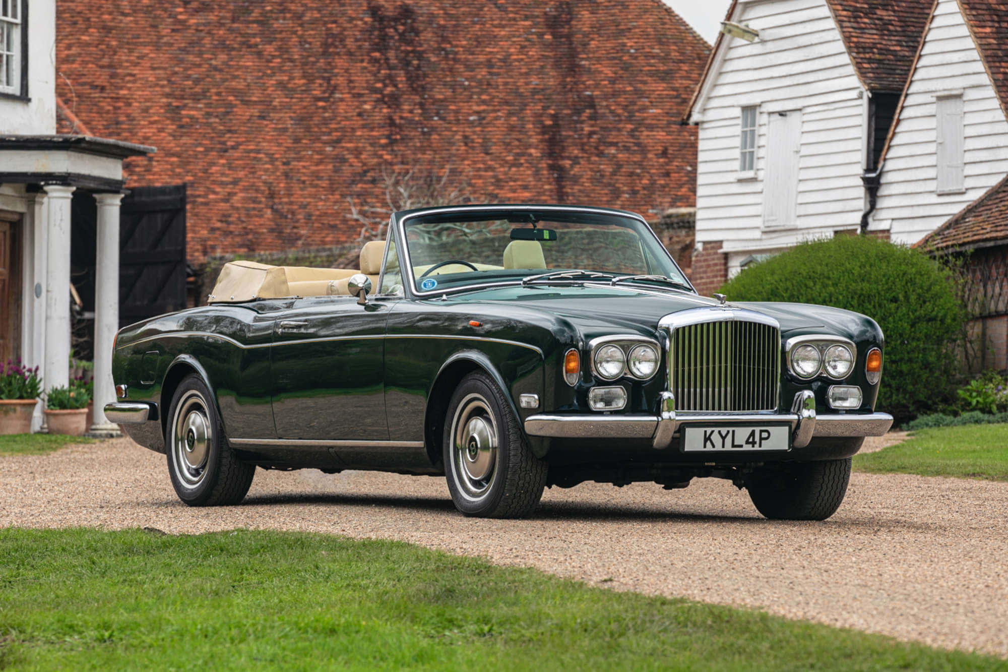 Bentley T1 桌布 壁紙 — 一架時尚的深綠色經典賓利開篷車停泊在碎石車道上，旁邊是傳統英式小屋，紅磚白木牆身。