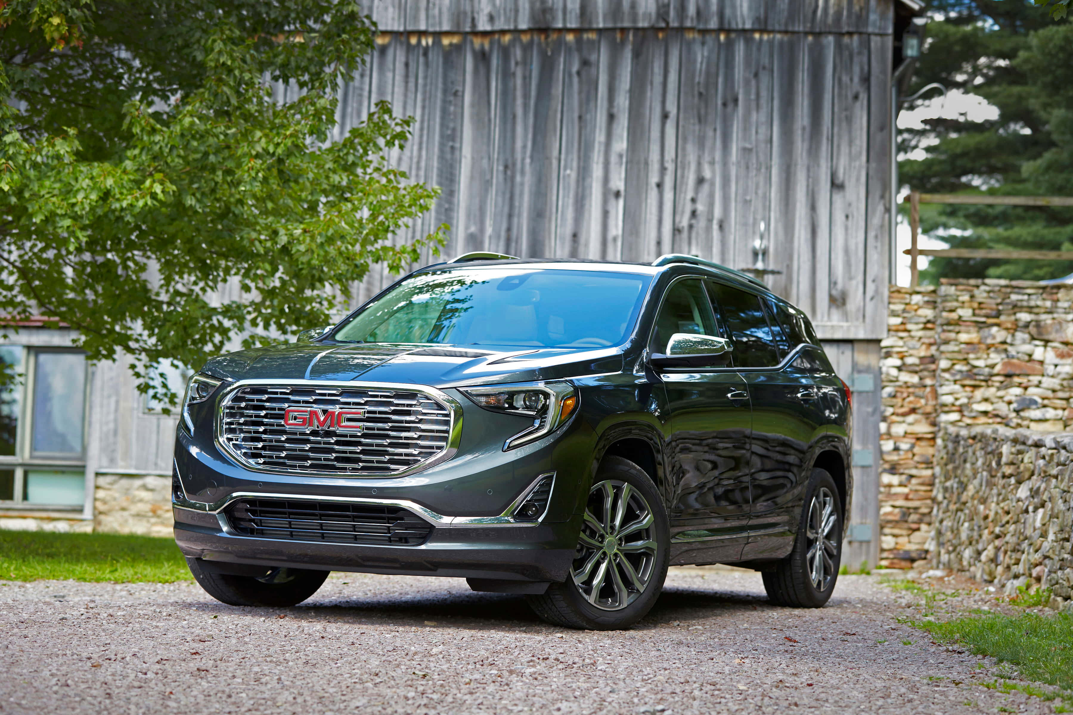 Gmc Terrain 桌布 壁紙 — 一輛時尚的深綠色GMC Acadia SUV停泊在碎石車道上，旁邊是質樸的木製穀倉和石牆。