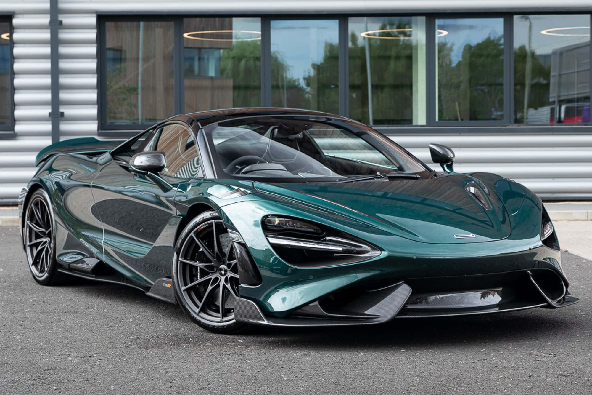 Mclaren 765lt 桌布 壁紙 — 一架時尚的翡翠綠色McLaren 720S跑車停泊在現代建築前的瀝青路上，建築物有大型窗戶。