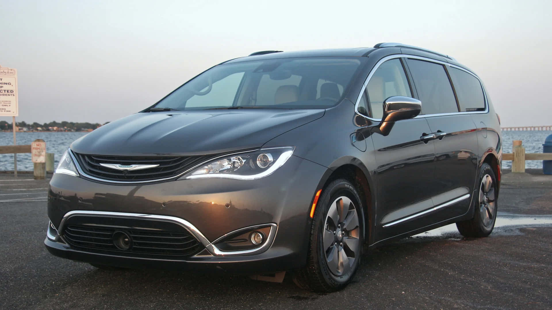 Chrysler Pacifica 桌布 壁紙 — 一架時尚的灰色 Chrysler Pacifica 小型貨車在黃昏時停泊在海濱，背景是平靜的水面和遠處的樹木。