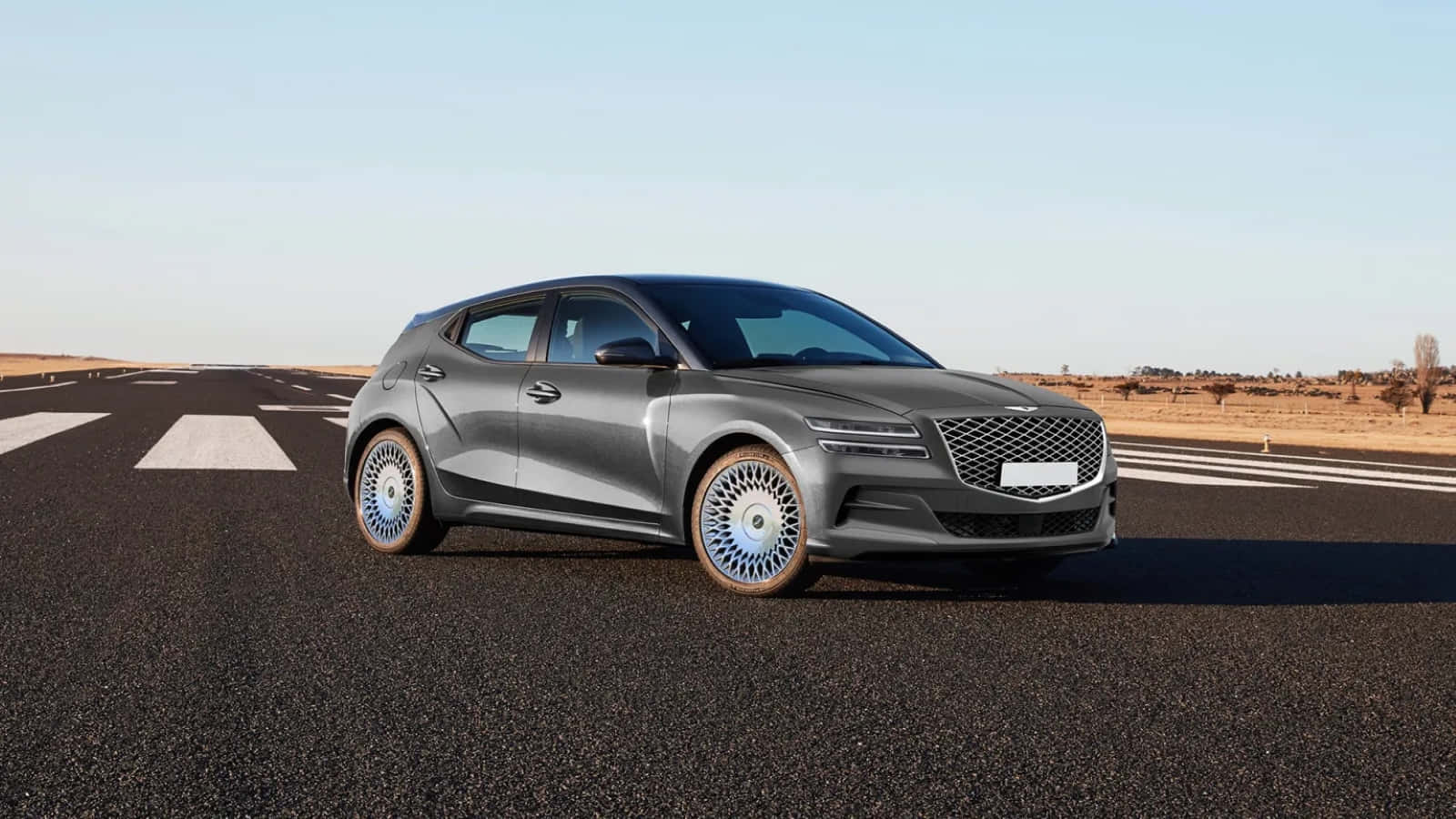 Genesis Gv60 桌布 壁紙 — 一輛時尚的灰色掀背車，帶有精緻的藍色輪圈，停在晴朗天空下的長長瀝青路中央。