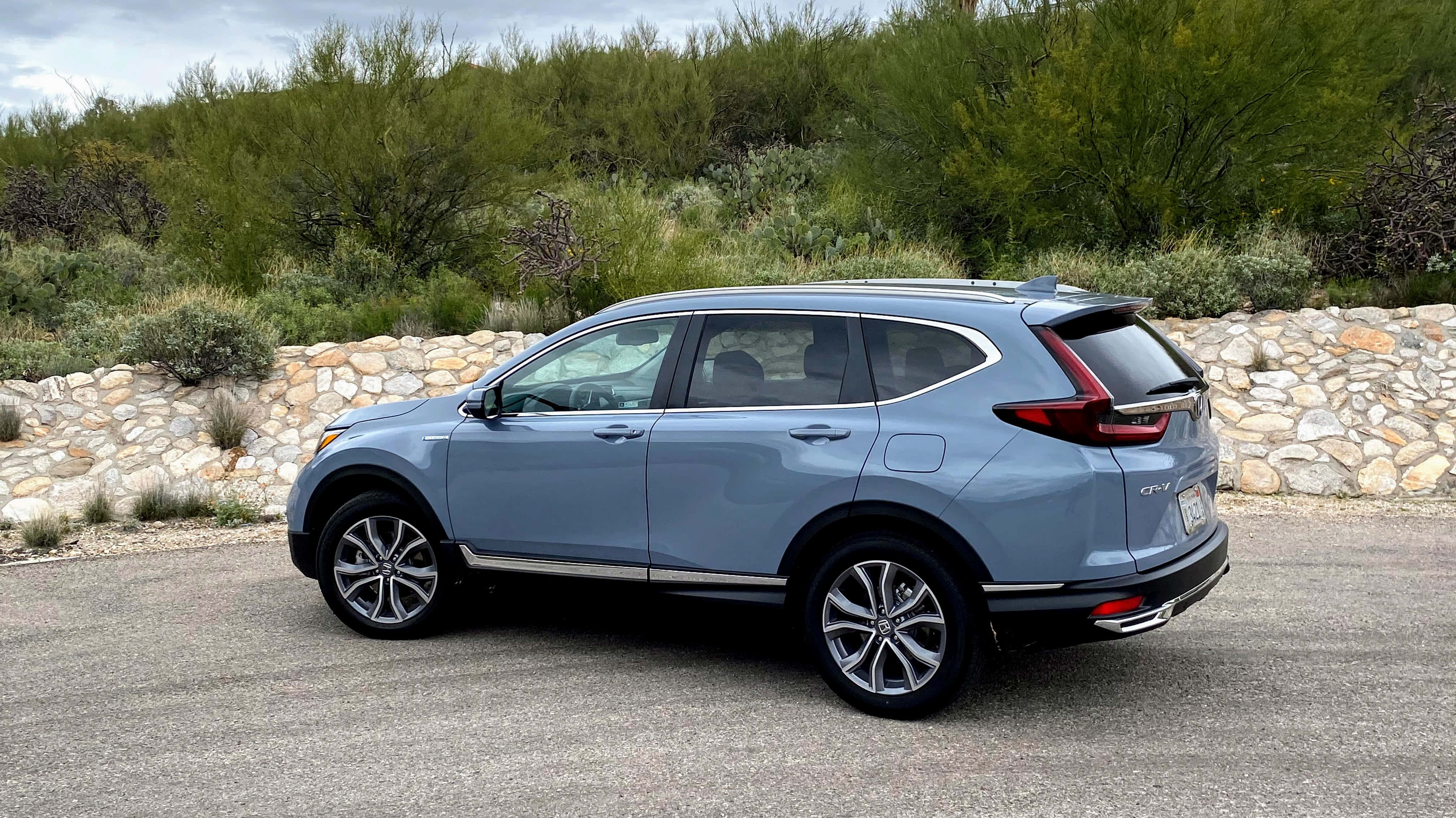Honda Cr-v 桌布 壁紙 — 一輛時尚的淺藍色本田CR-V SUV停在瀝青路上，旁邊是石牆和綠色灌木叢。