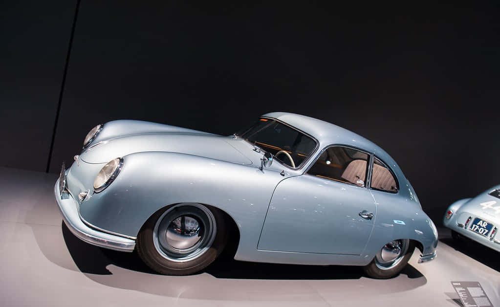 Porsche 356 桌布 壁紙 — 一架流線型淺藍色復古保時捷356跑車在黑暗博物館的聚光燈下閃閃發光。