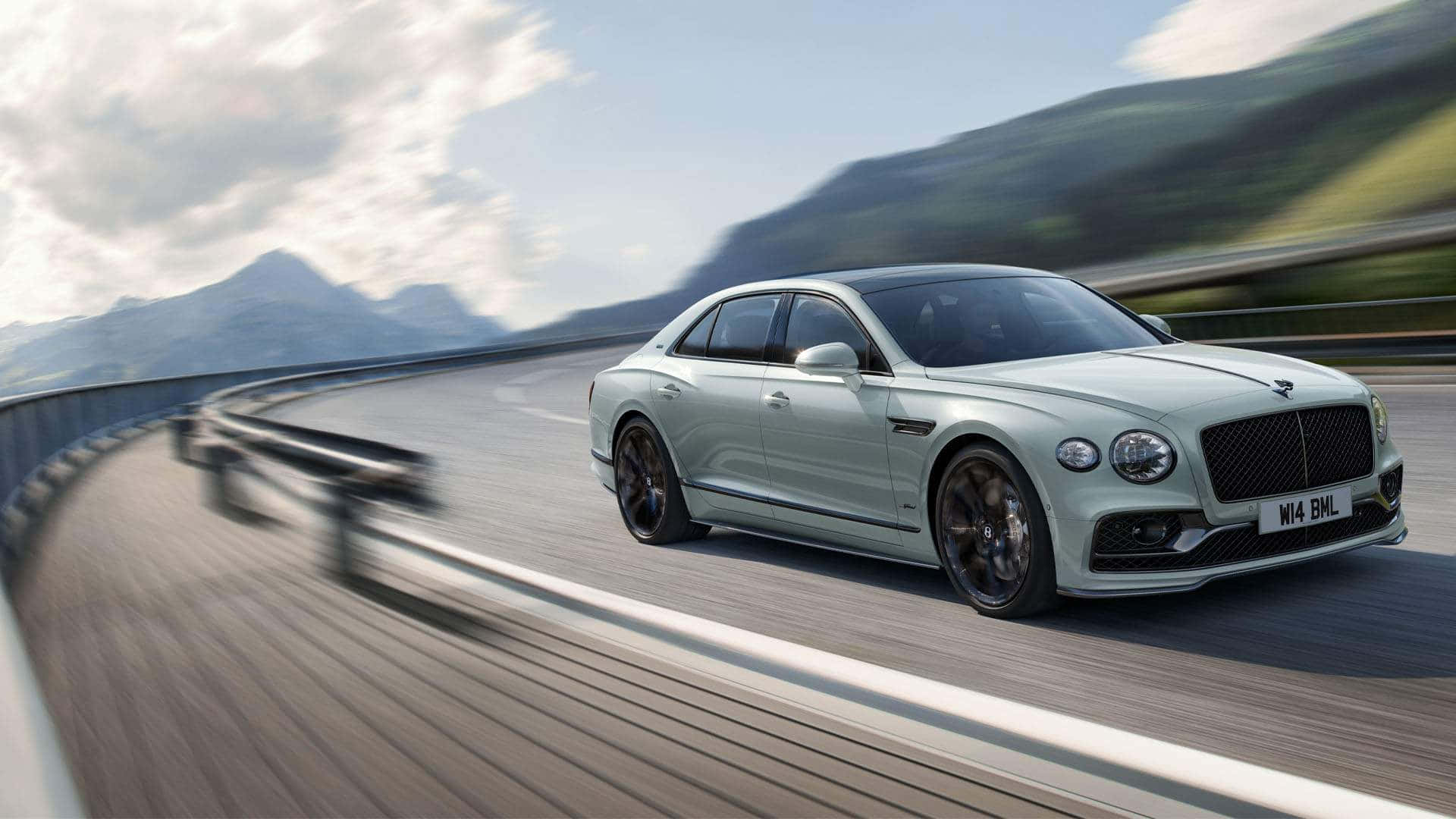 Bentley Mulsanne 桌布 壁紙 — 一輛時尚的淺綠色賓利飛馳在蜿蜒的山區高速公路上，天空部分多雲。