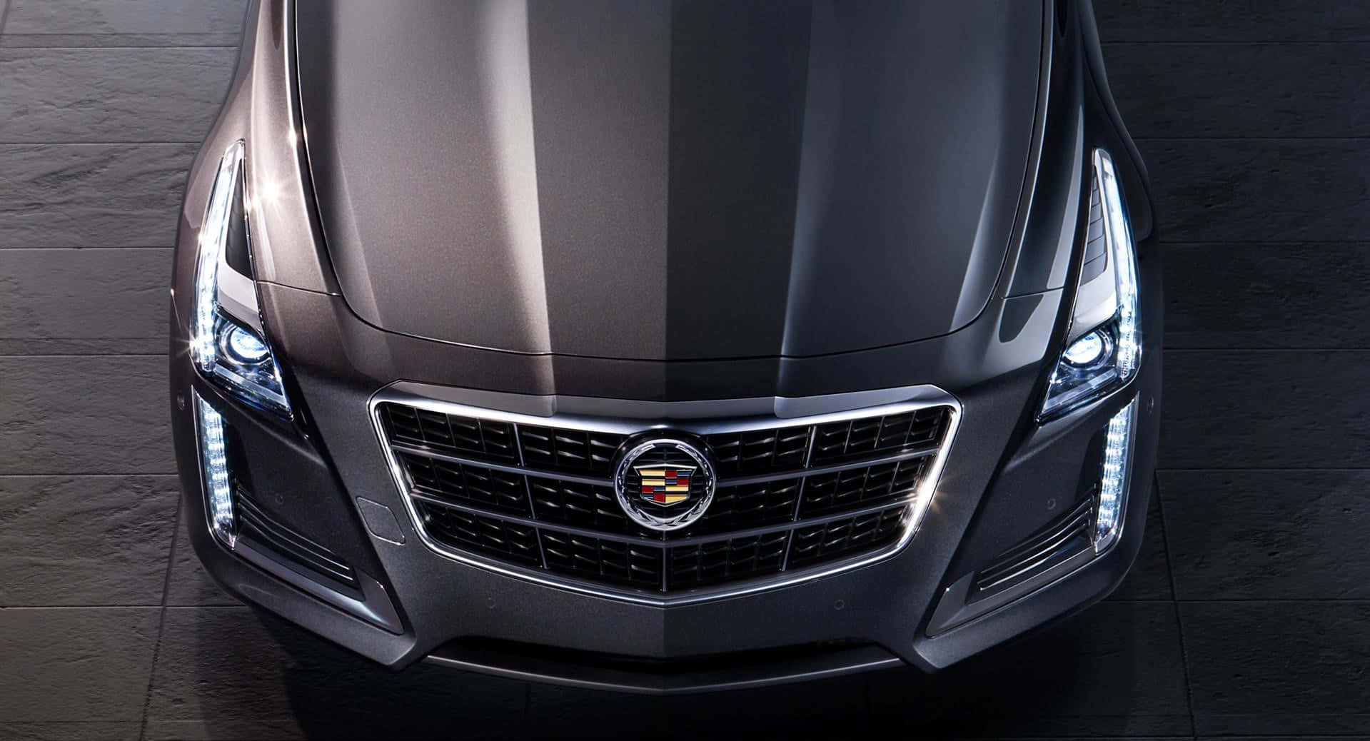 Cadillac Cts 桌布 壁紙 — 一輛時尚的啞光黑色凱迪拉克轎車正面視圖，在深色瓷磚地板上帶有發光的車頭燈。