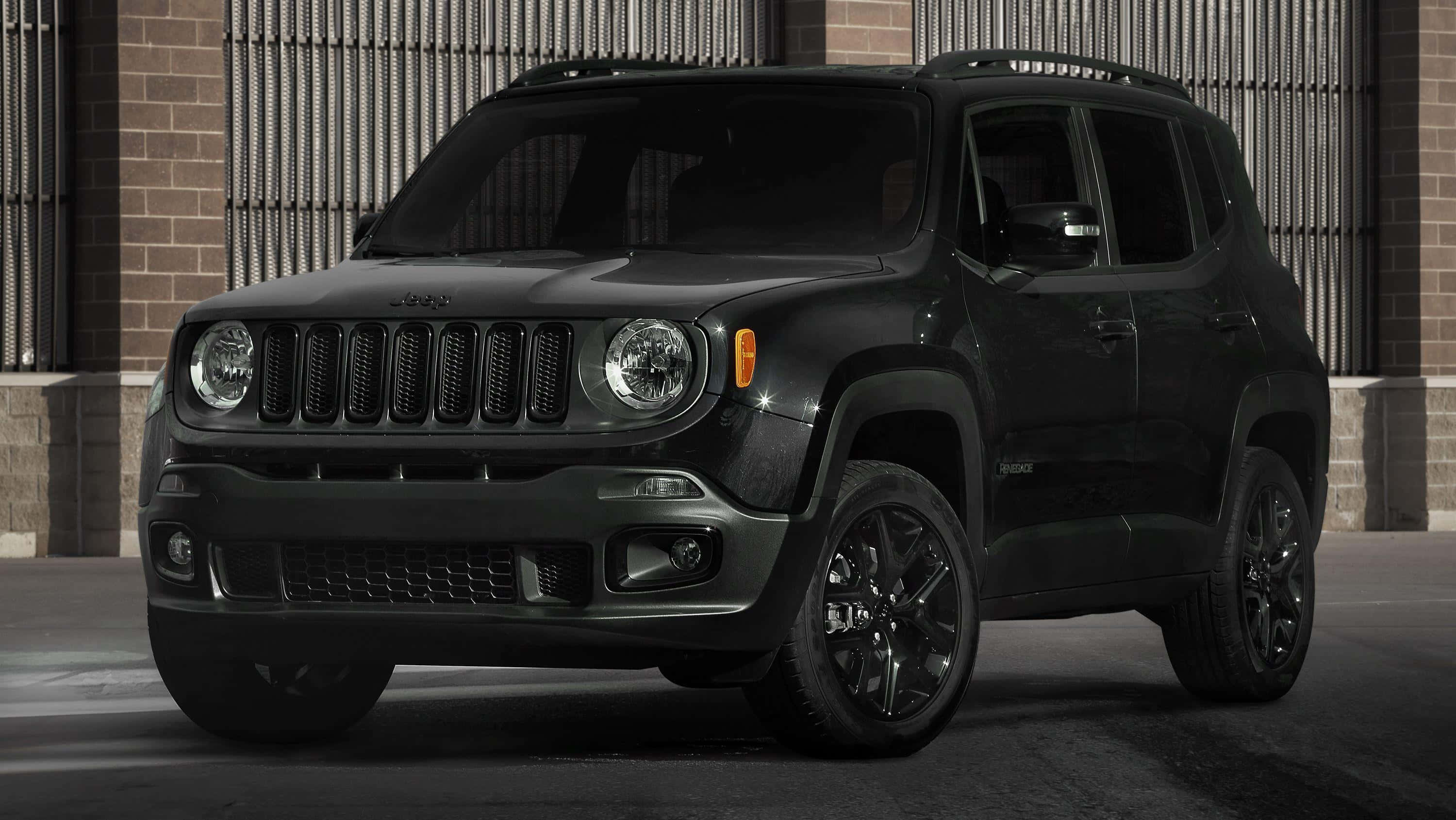 Jeep Renegade 桌布 壁紙 — 一輛時尚的啞光黑色Jeep Renegade SUV停在一棟帶金屬格柵的磚砌建築前。