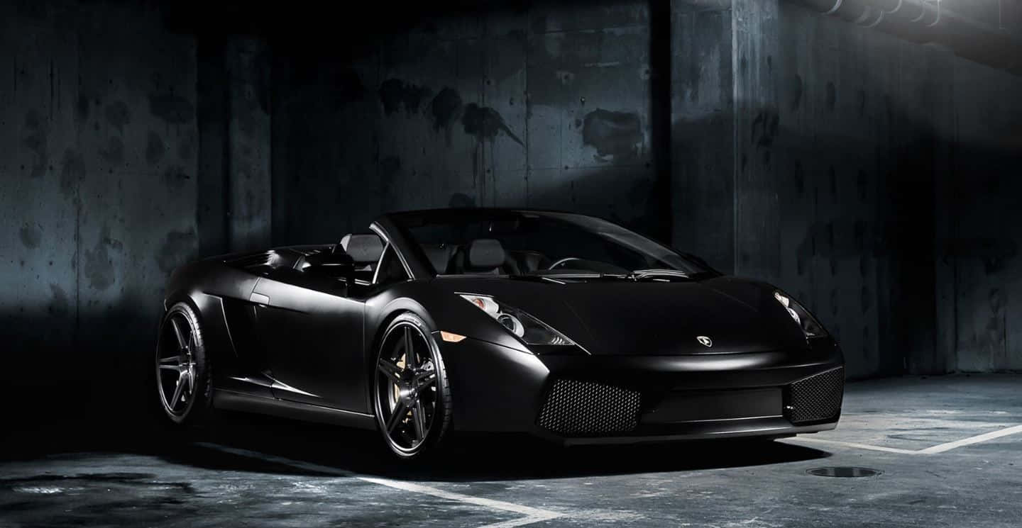 Lamborghini Gallardo 桌布 壁紙 — 一架型格啞黑色林寶堅尼Gallardo Spyder停泊在燈光昏暗的混凝土車庫中，配以戲劇性的聚光燈照明。