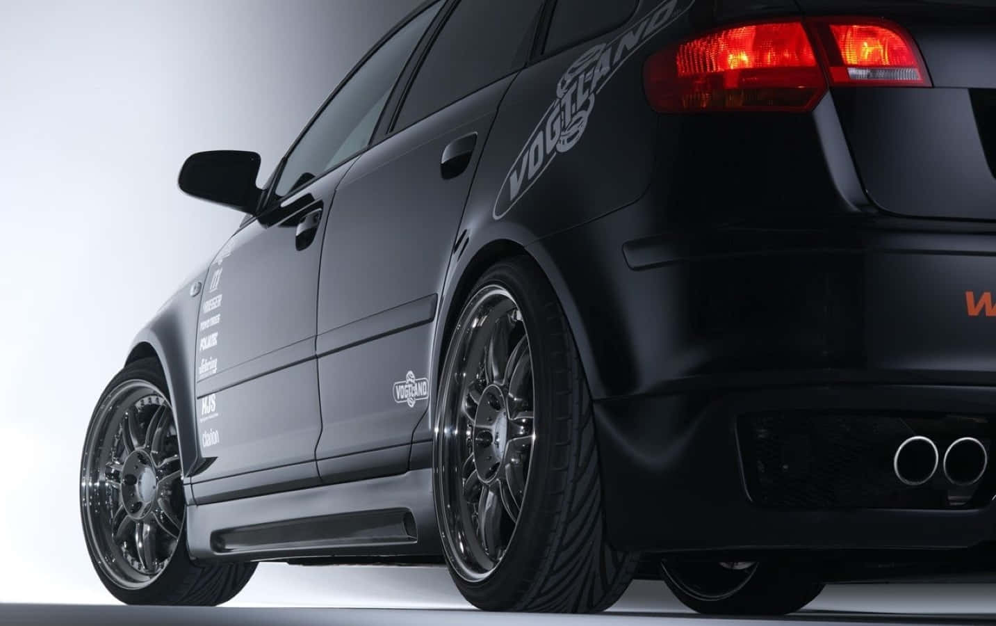 Audi A3 桌布 壁紙 — 一輛時尚的啞光黑色改裝轎車，配備定制輪轂和雙排氣管，在工作室燈光下閃耀。