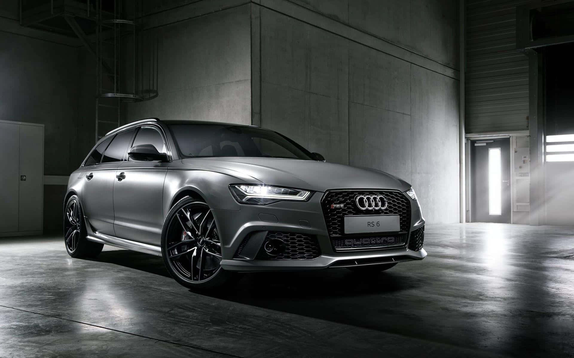 Audi Rs6 桌布 壁紙 — 一輛時尚的啞光灰色奧迪RS6 Avant旅行車在簡約工業倉庫中，混凝土牆壁和地板，燈光效果極具戲劇性。