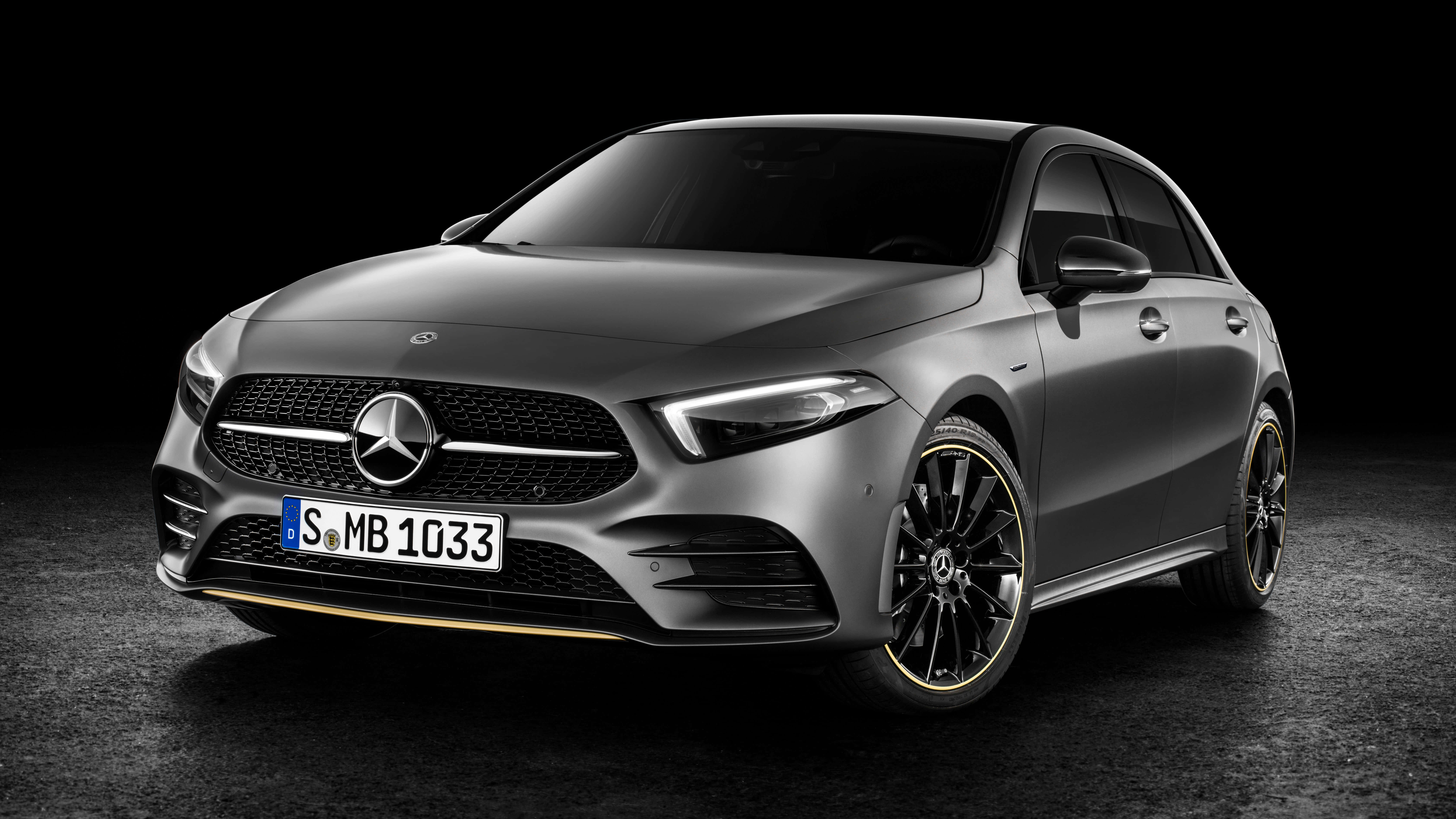 Mercedes Benz A-class 桌布 壁紙 — 一輛時尚的啞光灰色梅賽德斯-奔馳A級轎車，配備黑色輪圈和金色飾邊，在黑暗的攝影棚背景下展示。