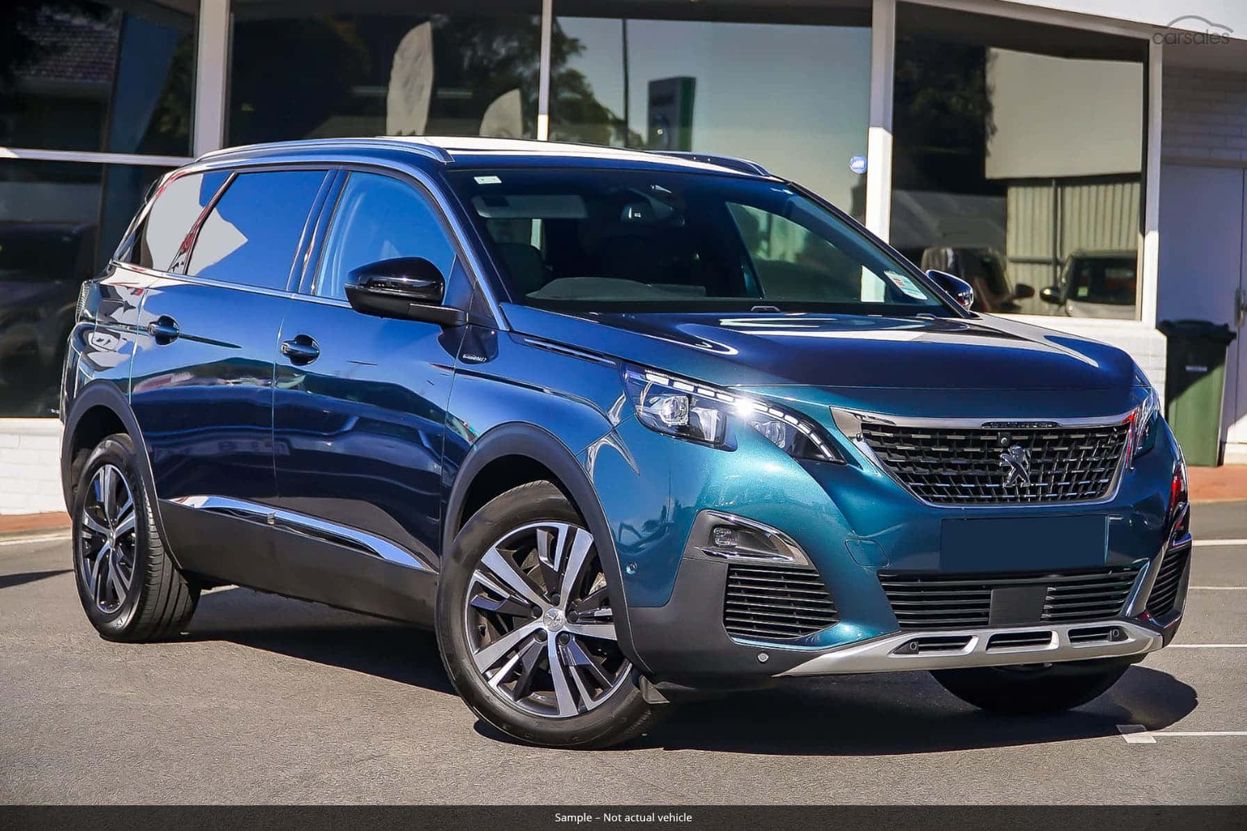 Peugeot 5008 桌布 壁紙 — 一輛時尚的金屬藍色標緻SUV在明亮的日光下停泊在現代玻璃建築外。