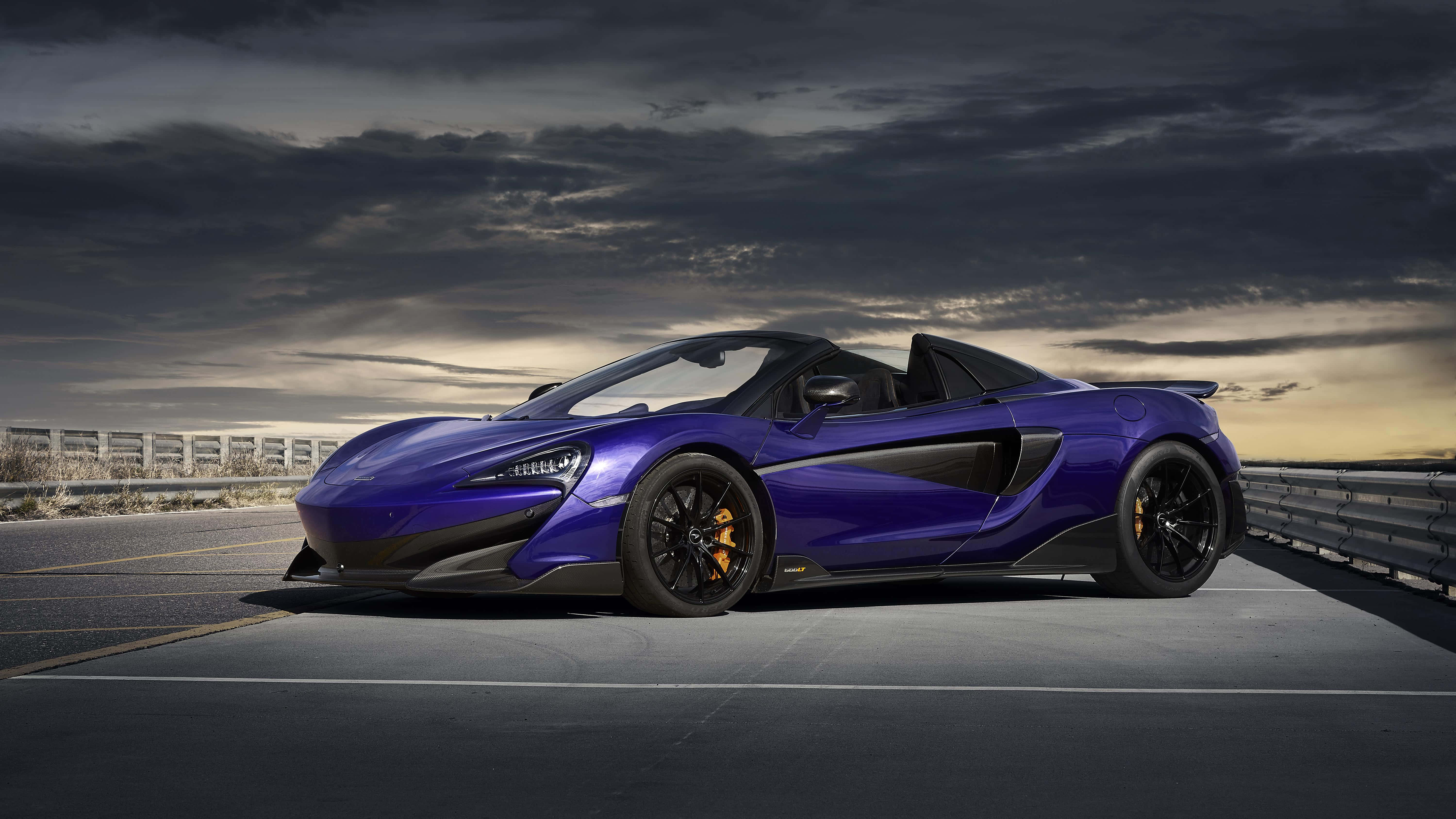 Mclaren 600lt 桌布 壁紙 — 一架時尚的紫色McLaren 570S Spider開篷跑車在黃昏時停泊在高速公路上，天空佈滿戲劇性的雲層。