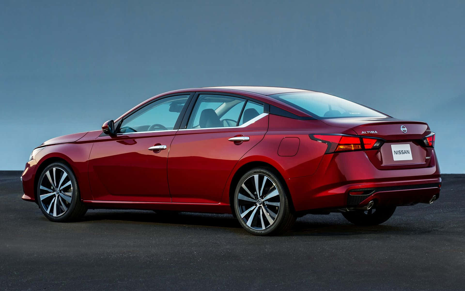 Nissan Altima 桌布 壁紙 — 一輛時尚的紅色日產Altima轎車在柔和藍灰色背景下的攝影棚燈光中閃閃發光。