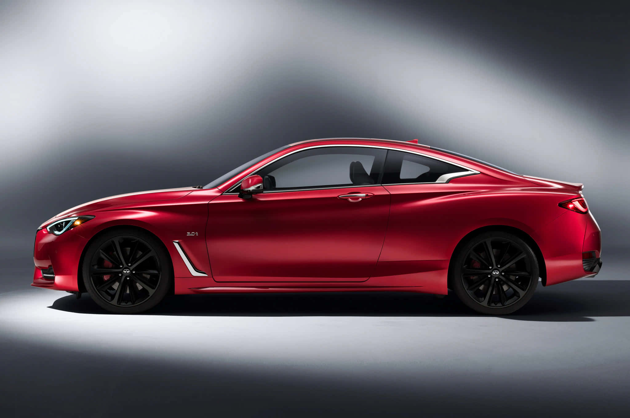 Infiniti Q60 桌布 壁紙 — 一輛時尚的紅色運動轎跑車在戲劇性的攝影棚燈光下，在灰色漸變背景上閃閃發光。