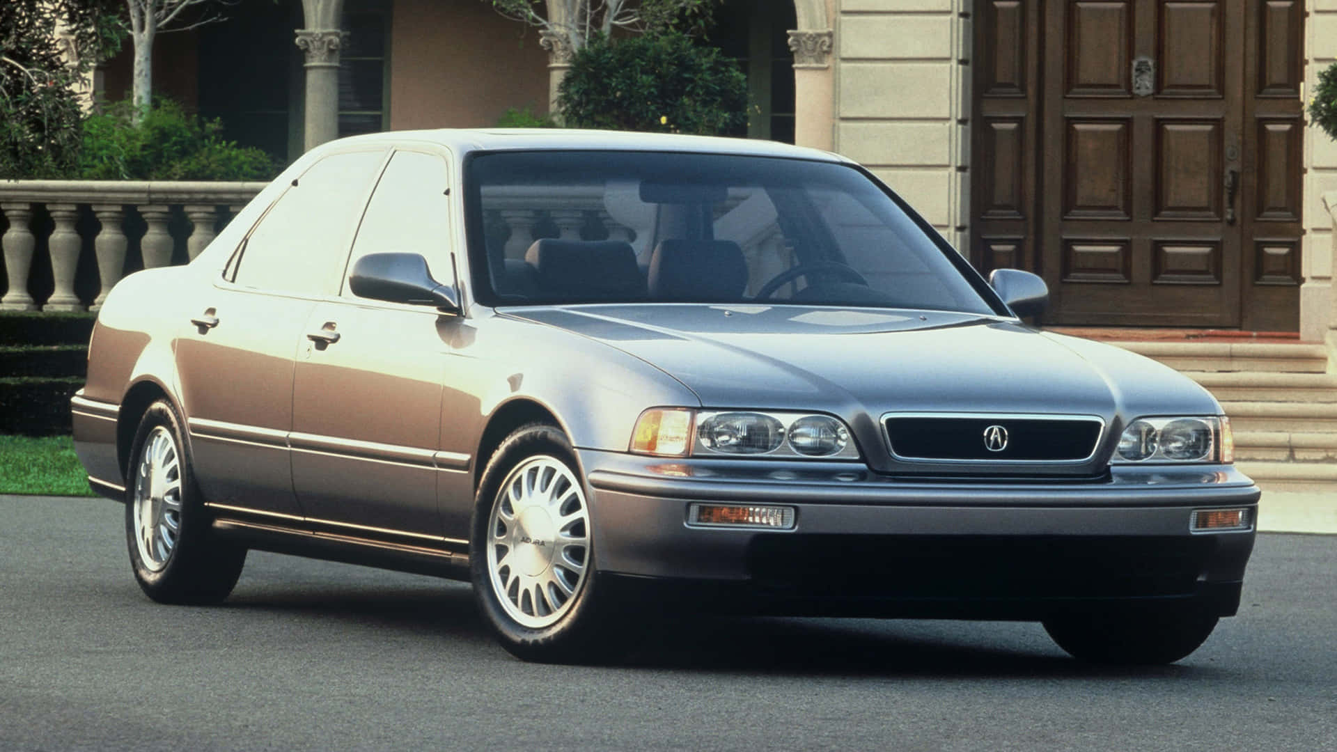 Acura Legend 桌布 壁紙 — 一輛時尚的銀色Acura轎車停泊在一棟有木門和石柱的豪宅前的車道上。