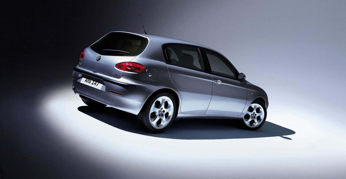 Alfa Romeo 147 桌布 壁紙 — 一輛時尚的銀色愛快羅密歐147掀背車在簡約漸變工作室背景下方戲劇性地照亮。