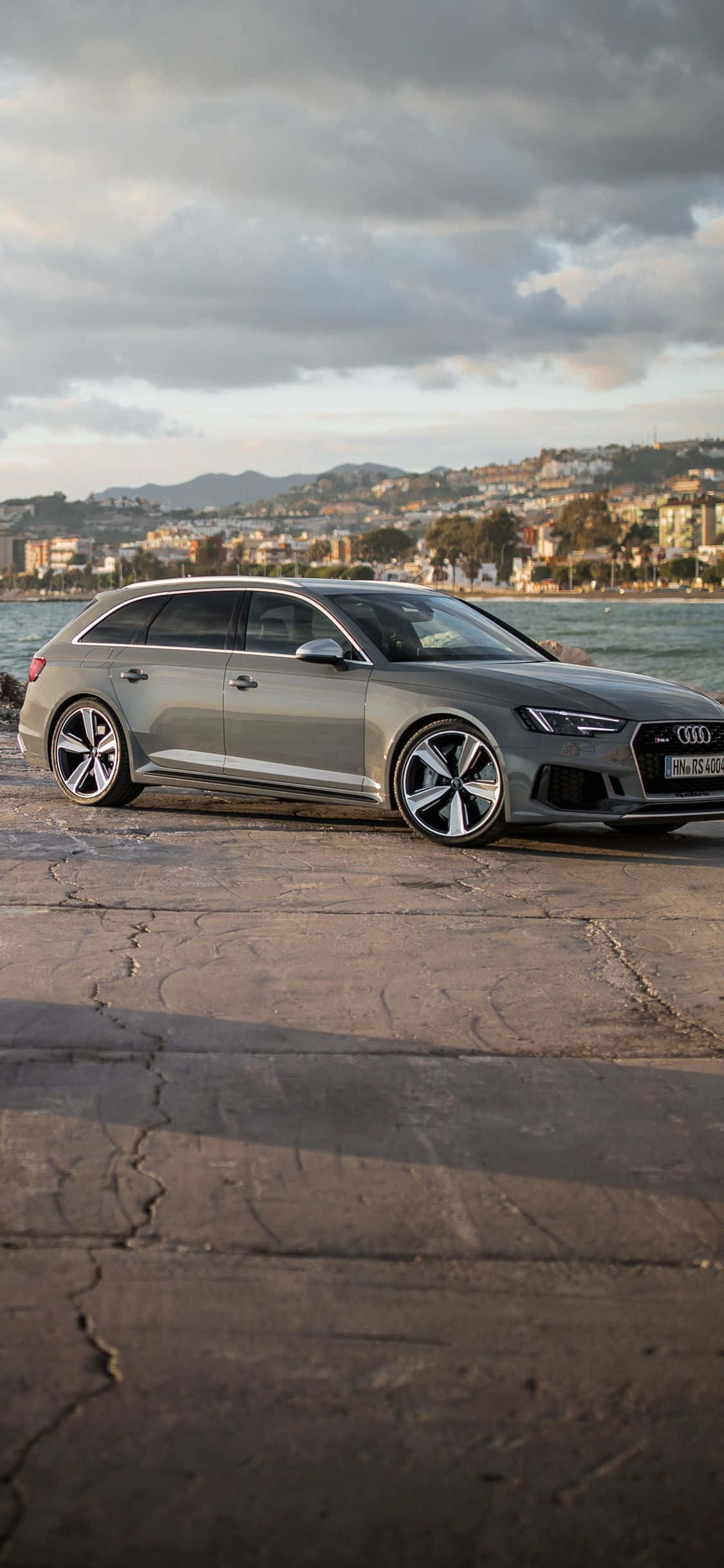 Audi Rs5 桌布 壁紙 — 一架時尚的銀色 Audi 旅行車停泊在海邊裂開的混凝土上，天空多雲。