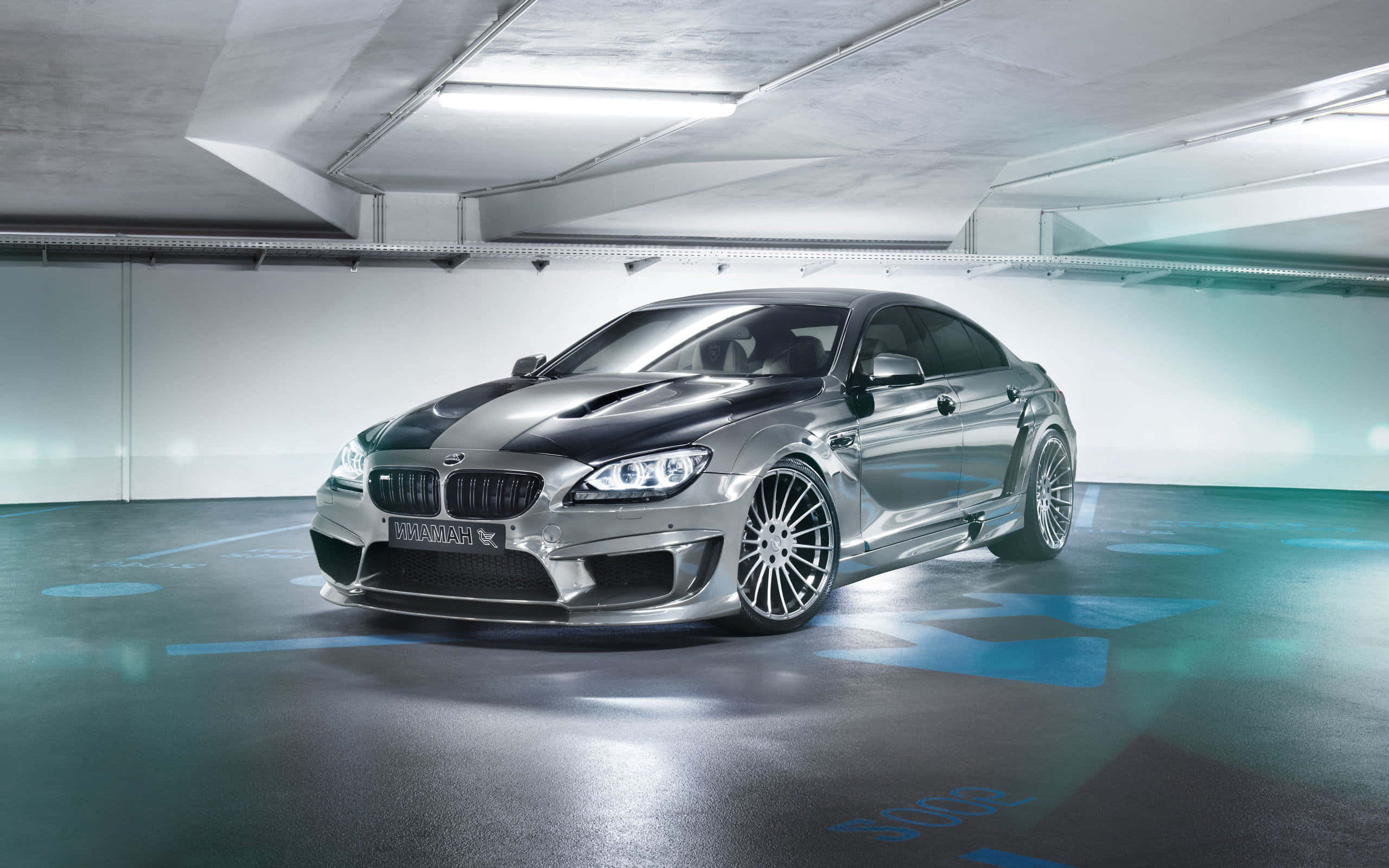 Bmw M6 桌布 壁紙 — 一輛時尚的銀色BMW M6，帶有黑色引擎蓋條紋，在簡約地下停車場的螢光燈下閃閃發光。