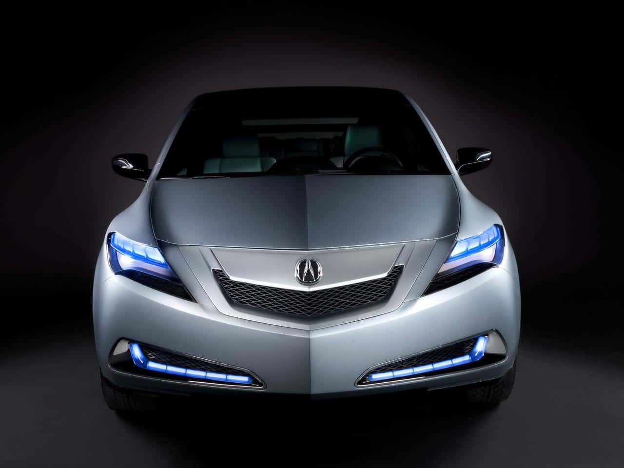 Acura Tsx 桌布 壁紙 — 一輛時尚的銀色汽車，帶有發光的藍色車頭燈，在黑暗的攝影棚背景下向前凝視。