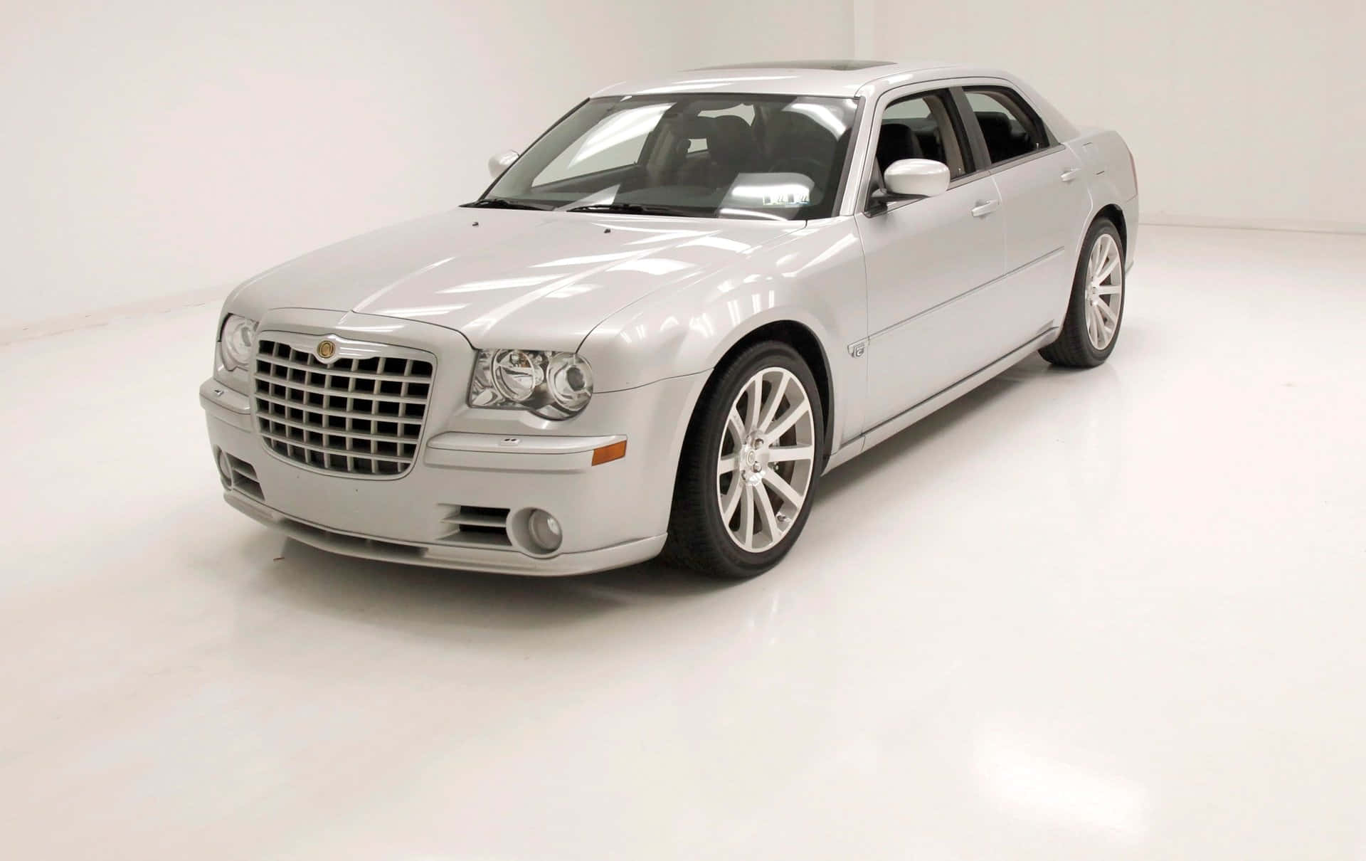 Chrysler 300 桌布 壁紙 — 一輛時尚的銀色 Chrysler 300 轎車在明亮的攝影棚燈光下，於純白背景前閃閃發光。