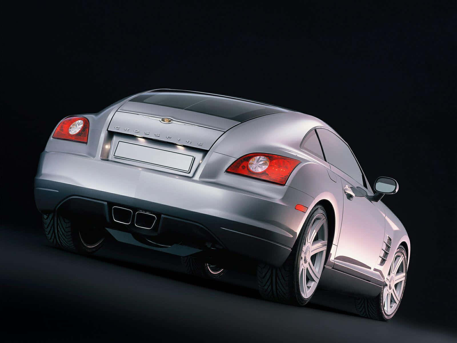 Chrysler Crossfire 桌布 壁紙 — 一輛時尚的銀色 Chrysler Crossfire 跑車，從後方四分之三角度展示，背景為深色工作室。