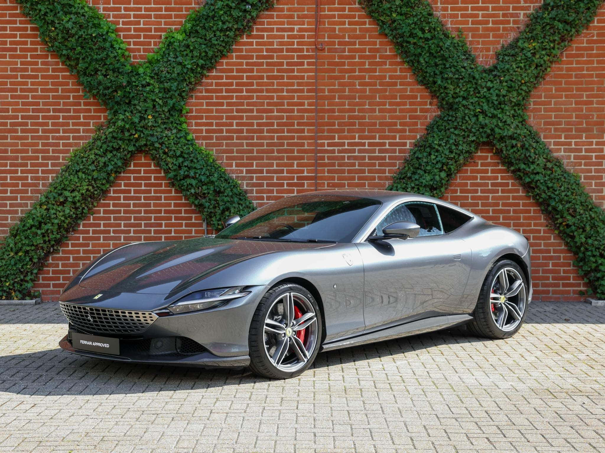 Ferrari Roma 桌布 壁紙 — 一架型格銀色法拉利 Roma 停泊在磚砌庭院，背景係紅磚牆，牆上綠色常春藤形成 X 形。