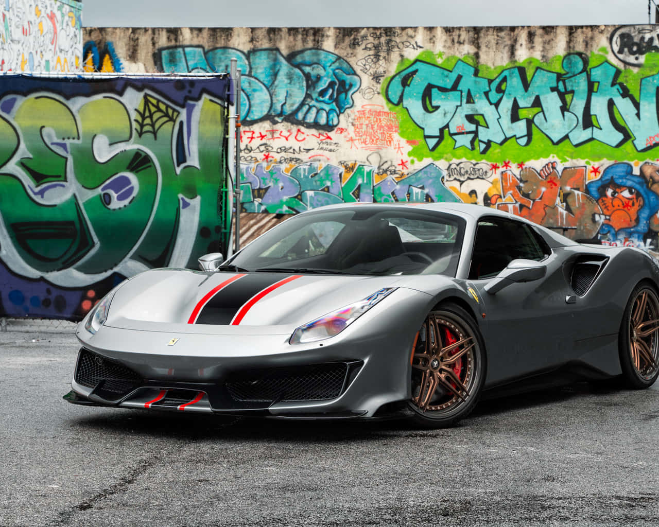 Ferrari 488 Spider 桌布 壁紙 — 一輛時尚的銀色法拉利跑車，帶有紅色和黑色條紋，停在充滿活力的塗鴉牆前。