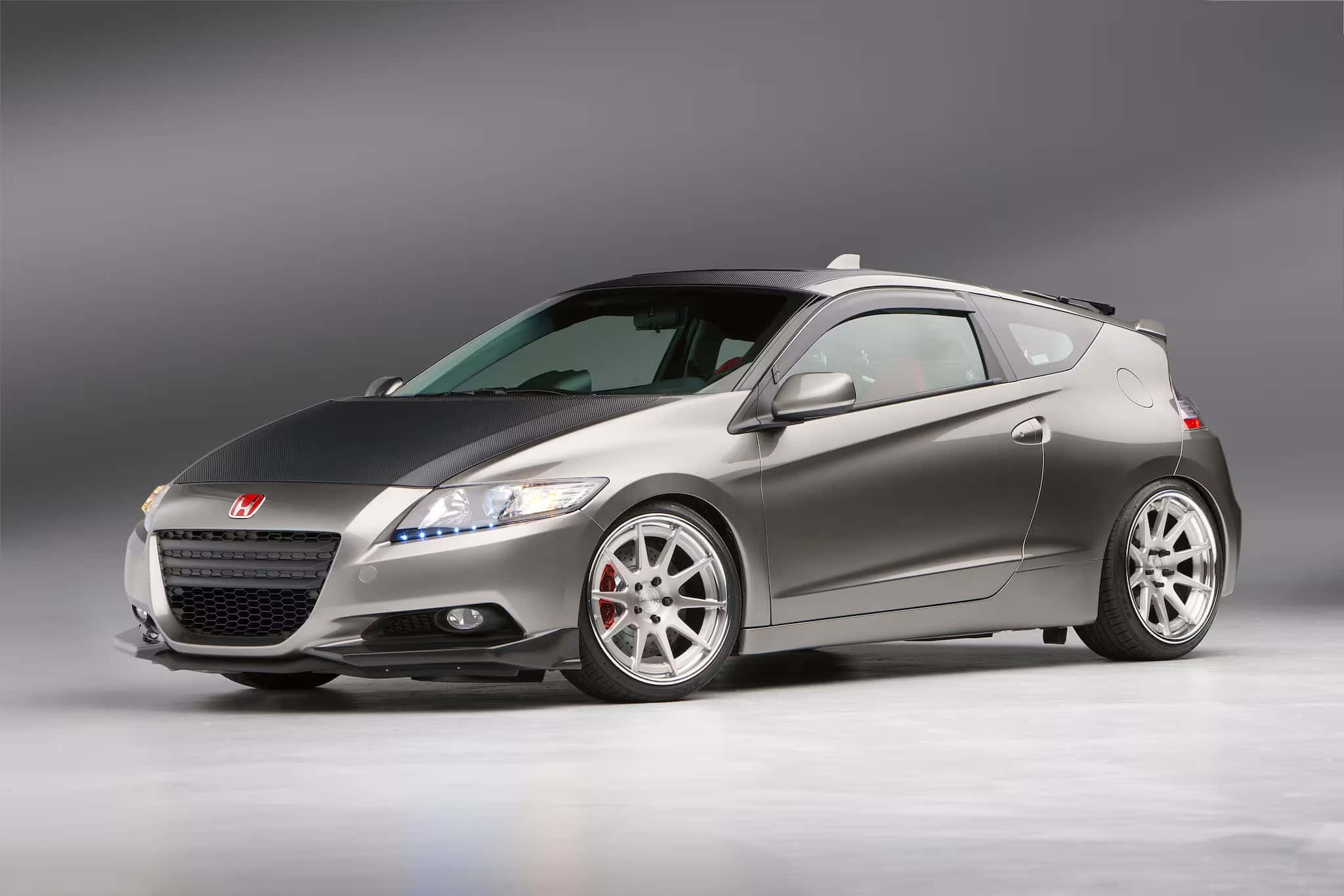 Honda Cr-z 桌布 壁紙 — 一輛時尚的銀色本田CR-Z跑車，配備黑色引擎蓋和紅色制動卡鉗，在漸變灰色工作室背景前擺姿勢。