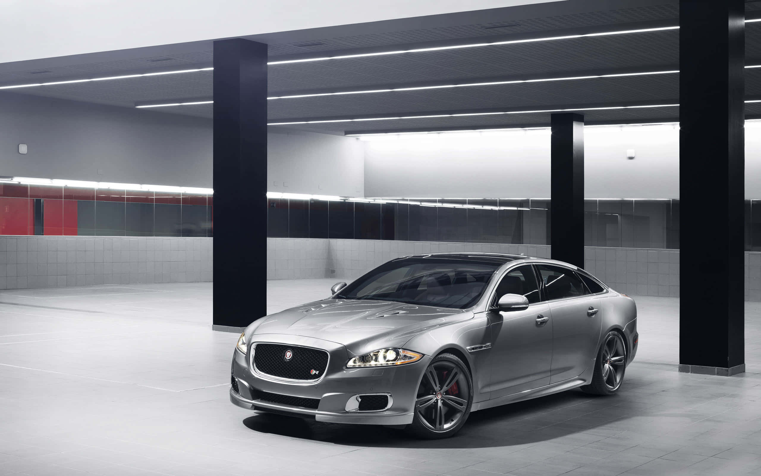Jaguar Xjr 桌布 壁紙 — 一輛時尚的銀色積架XJ轎車在簡約現代停車場的明亮螢光燈下閃閃發光。