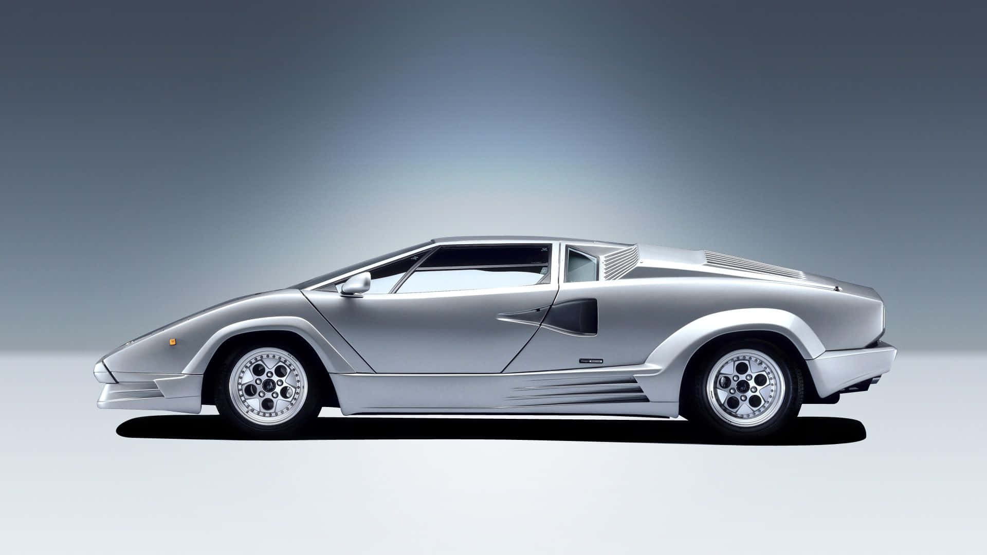 Lamborghini Countach 桌布 壁紙 — 一輛時尚的銀色林寶堅尼Countach跑車在灰色漸變工作室背景中以側面展示。
