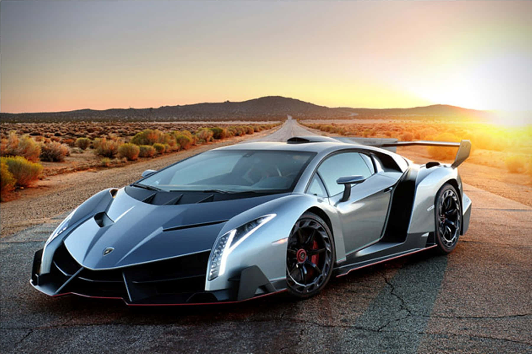 Lamborghini Veneno 桌布 壁紙 — 一架流線型銀色林寶堅尼 Veneno 停泊在沙漠公路上，夕陽的金色光芒投下長長的影子。