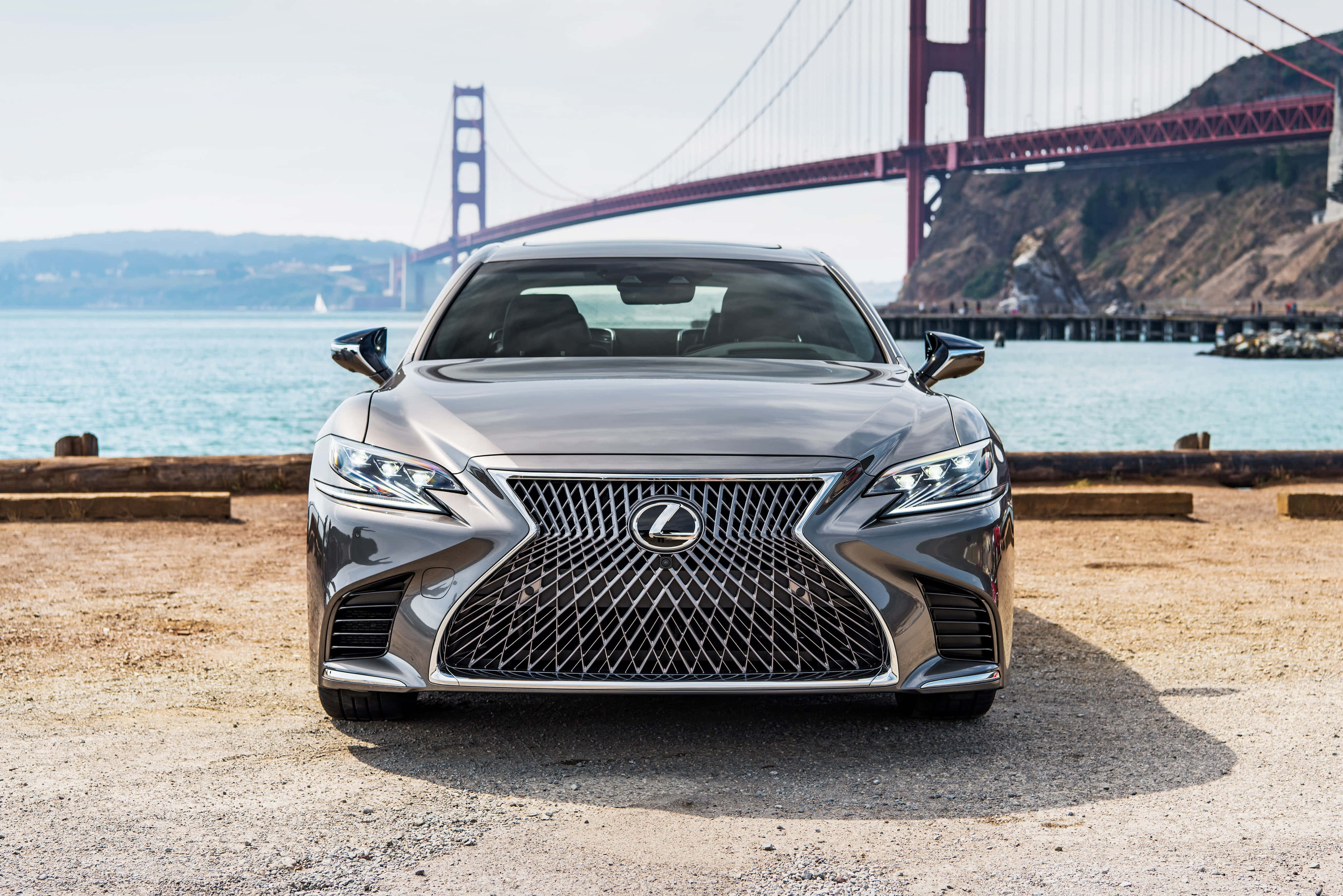 Lexus Ls 500 桌布 壁紙 — 一架時尚的銀色凌志房車面向前方，停在碎石碼頭上，背景是標誌性的金門大橋和藍色海灣水域。