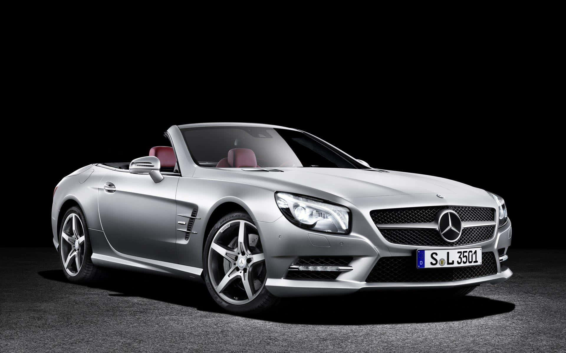 Mercedes Benz Sl-class 桌布 壁紙 — 一輛時尚的銀色梅賽德斯-奔馳SL敞篷車配備紅色皮革座椅，在工作室燈光下以純黑背景展示。