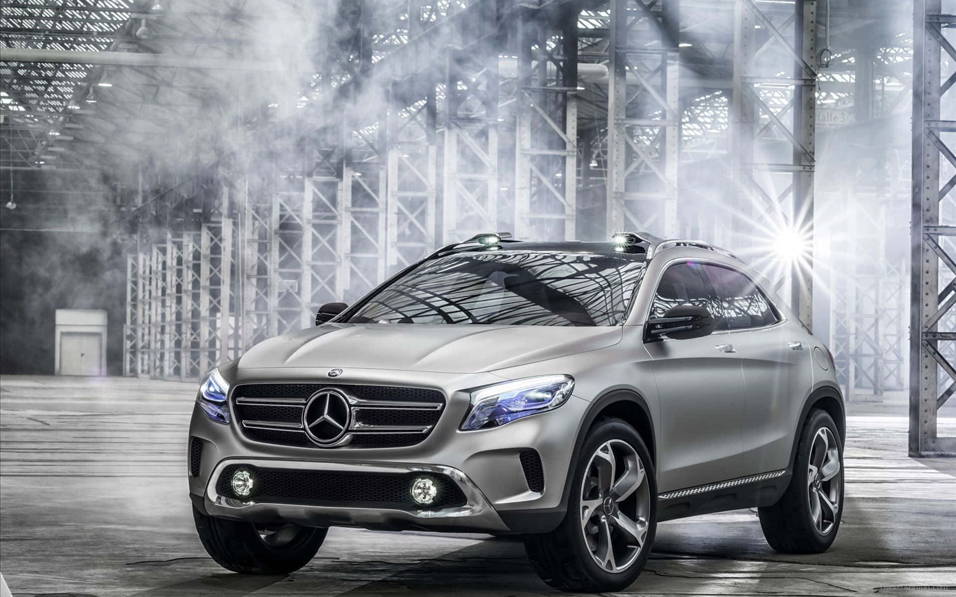 Mercedes Benz Gla-class 桌布 壁紙 — 一輛時尚的銀色 Mercedes-Benz SUV 在煙霧瀰漫的工業倉庫中，被明亮的聚光燈照射出其現代設計，氣勢非凡。