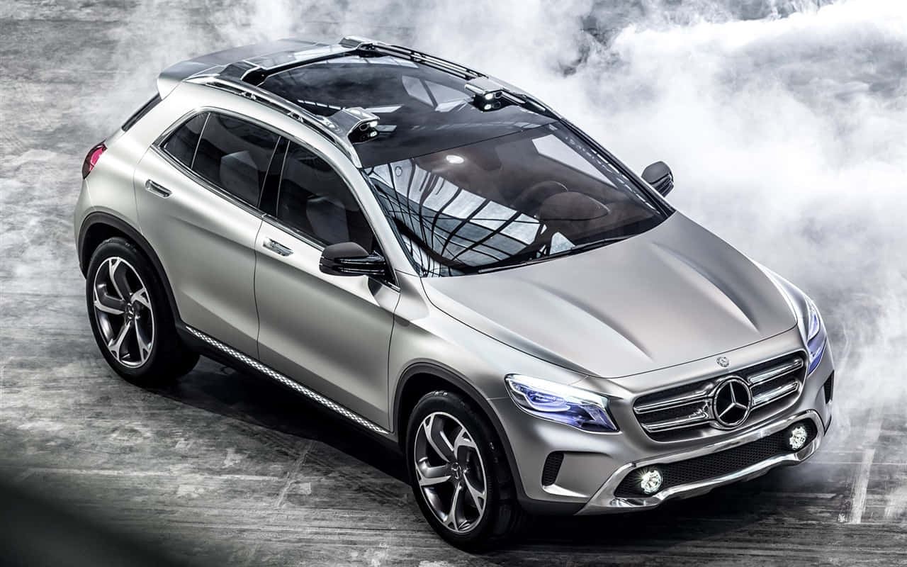 Mercedes Benz Gla-class 桌布 壁紙 — 一架時尚的銀色Mercedes-Benz SUV，配備車頂行李架和發光頭燈，站立在混凝土地面上，周圍環繞著旋轉的煙霧。