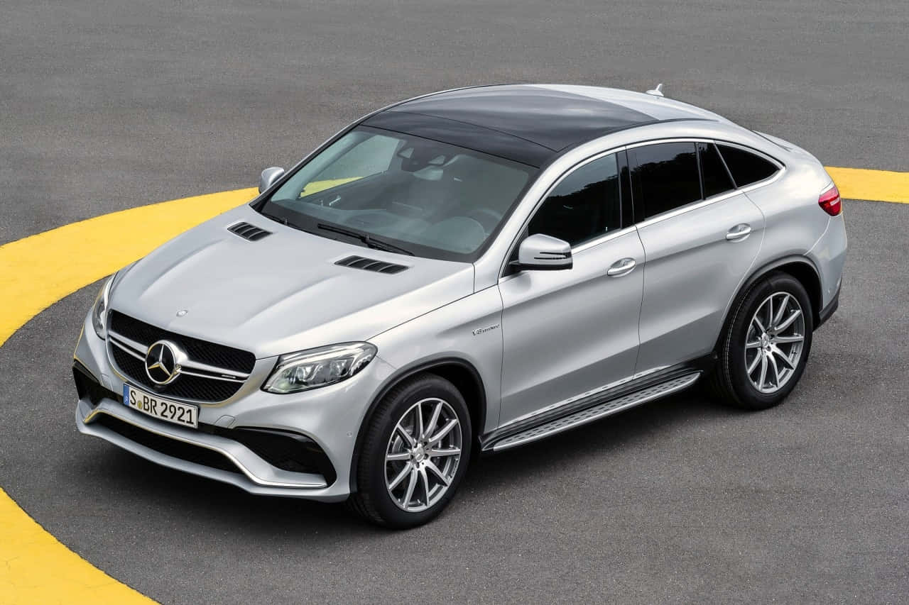 Mercedes Benz Gle-class 桌布 壁紙 — 一輛時尚的銀色 Mercedes GLE Coupe SUV 停泊在灰色地面上，帶有醒目的黃色彎曲線條。