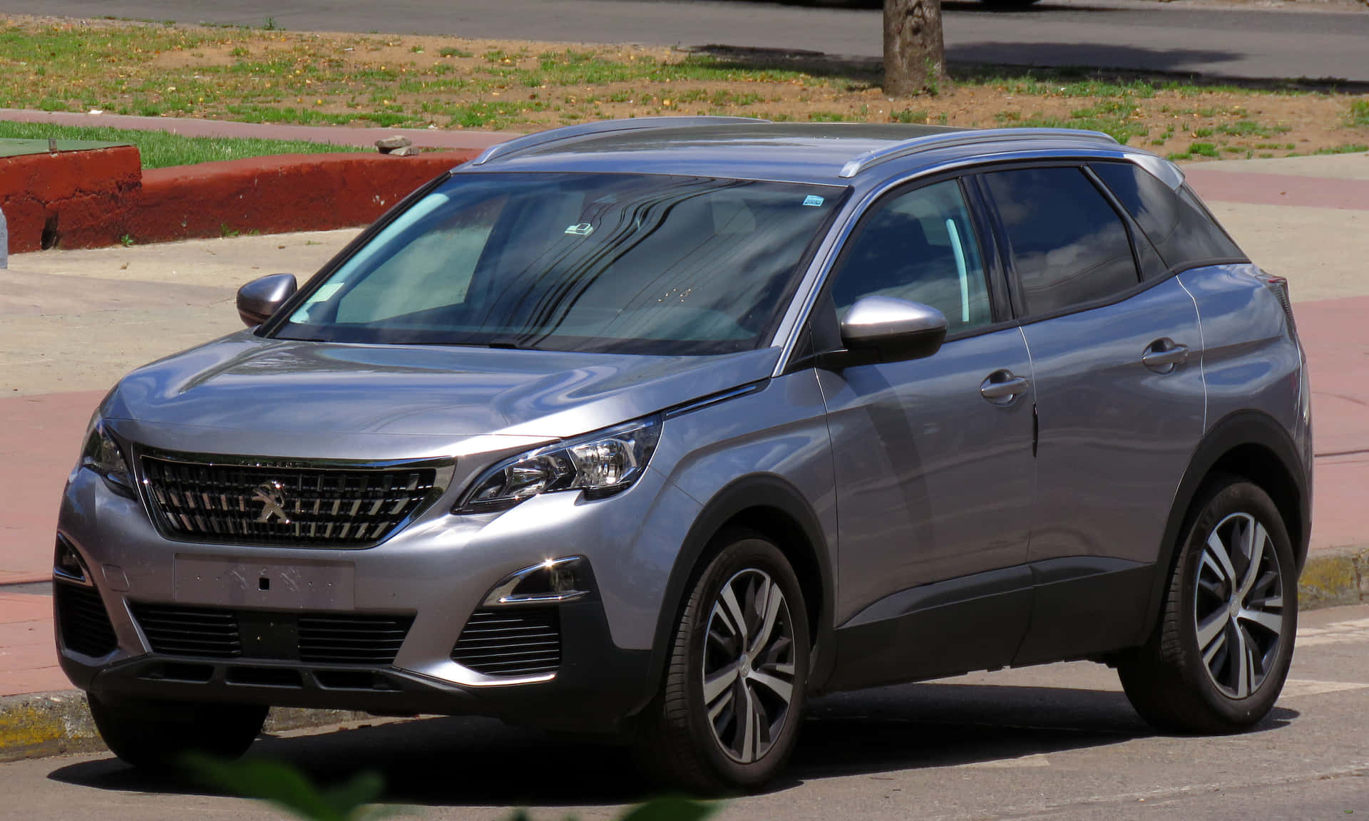  壁紙 — 一輛時尚的銀色Peugeot SUV停泊在陽光普照的市區街道上，背景有綠化和行人路。