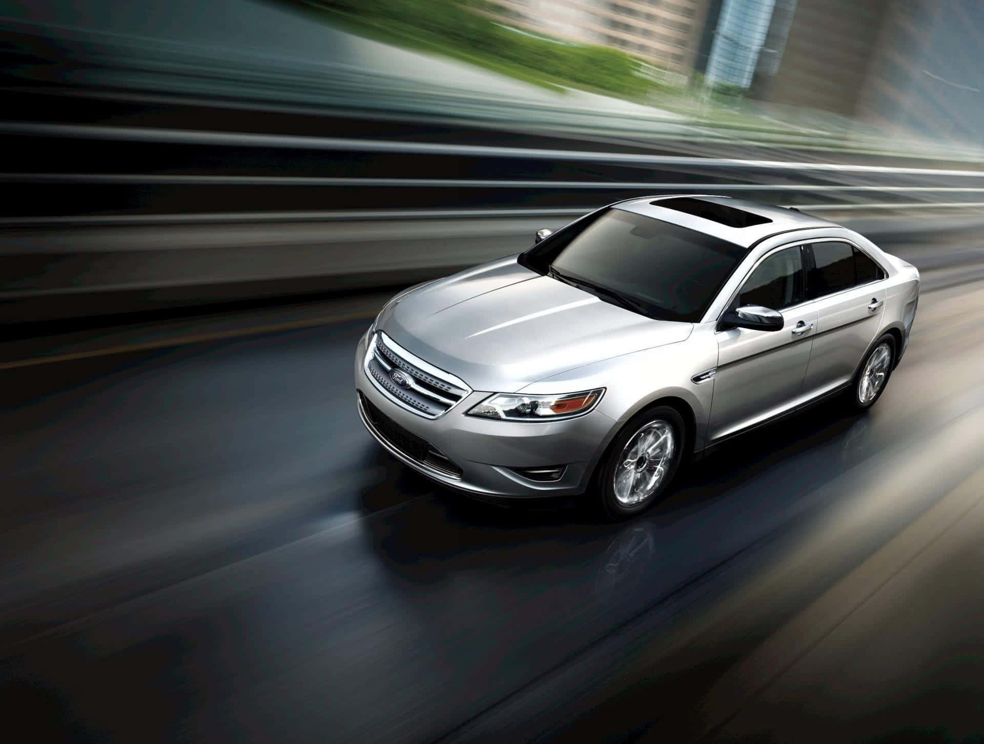 Ford Taurus 桌布 壁紙 — 一架時尚的銀色轎車在模糊的城市高速公路上疾馳，動態模糊效果強調了速度。