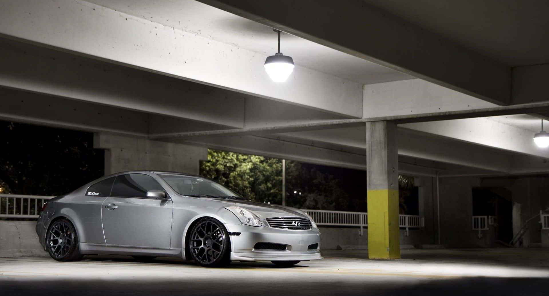 Infiniti G35 桌布 壁紙 — 一輛時尚的銀色跑車在夜間停泊在混凝土天橋下，由單個吊燈照亮。