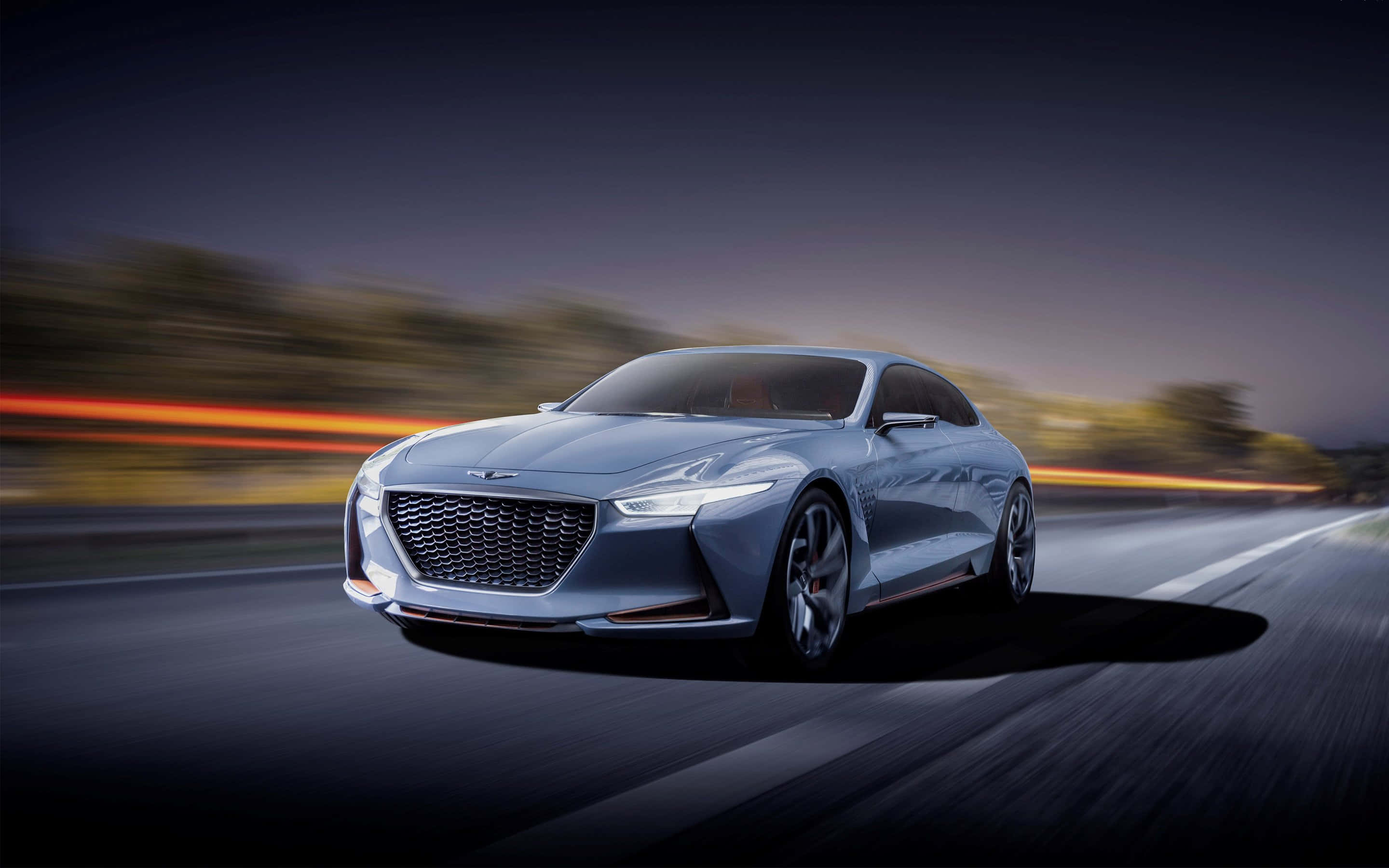 Genesis G70 桌布 壁紙 — 一輛時尚的銀色跑車在黃昏時分沿著高速公路疾馳，模糊的橙色燈光掠過。