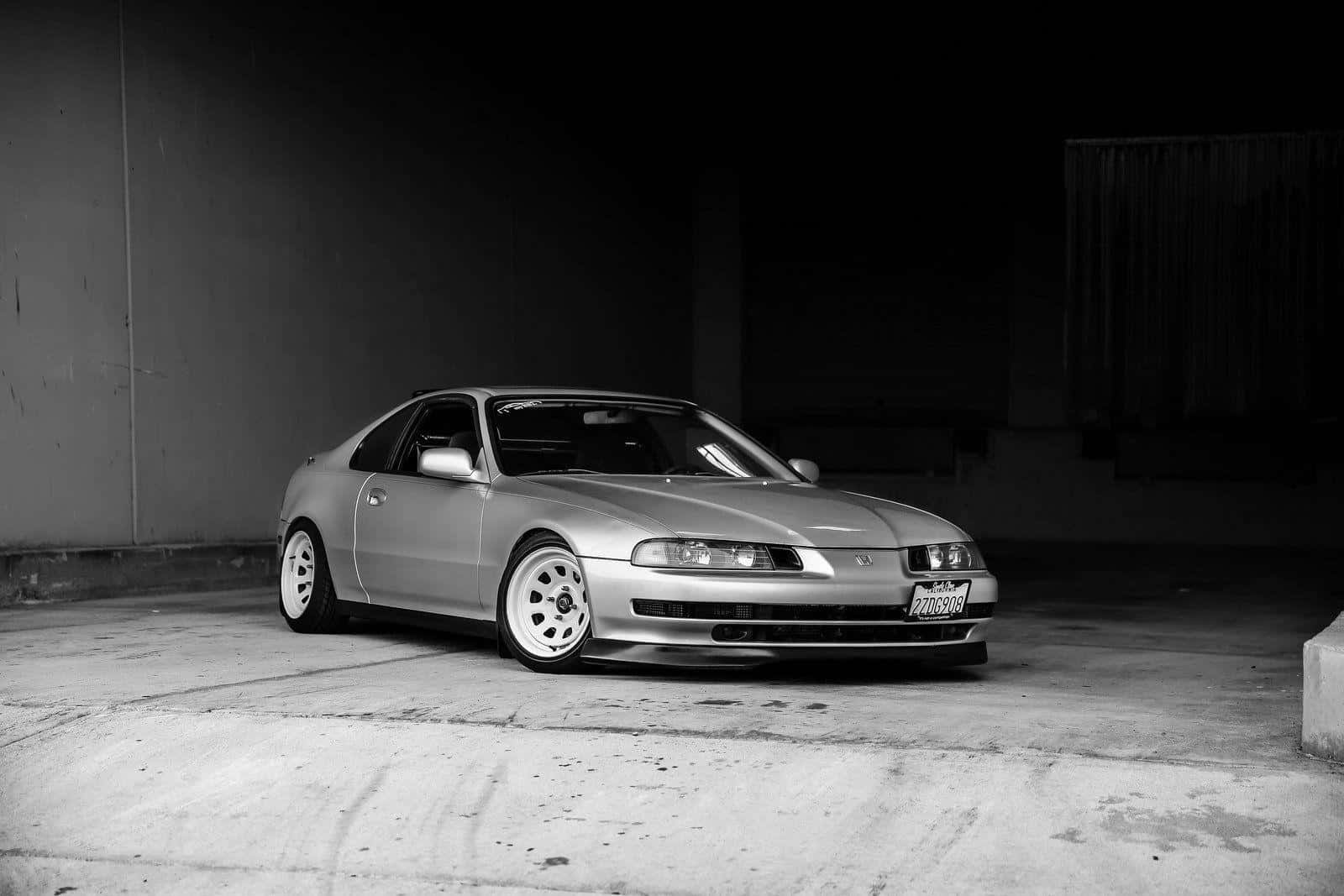 Honda Prelude 桌布 壁紙 — 一輛時尚的銀色跑車配白色輪胎，夜晚停泊在燈光昏暗的混凝土車庫中。