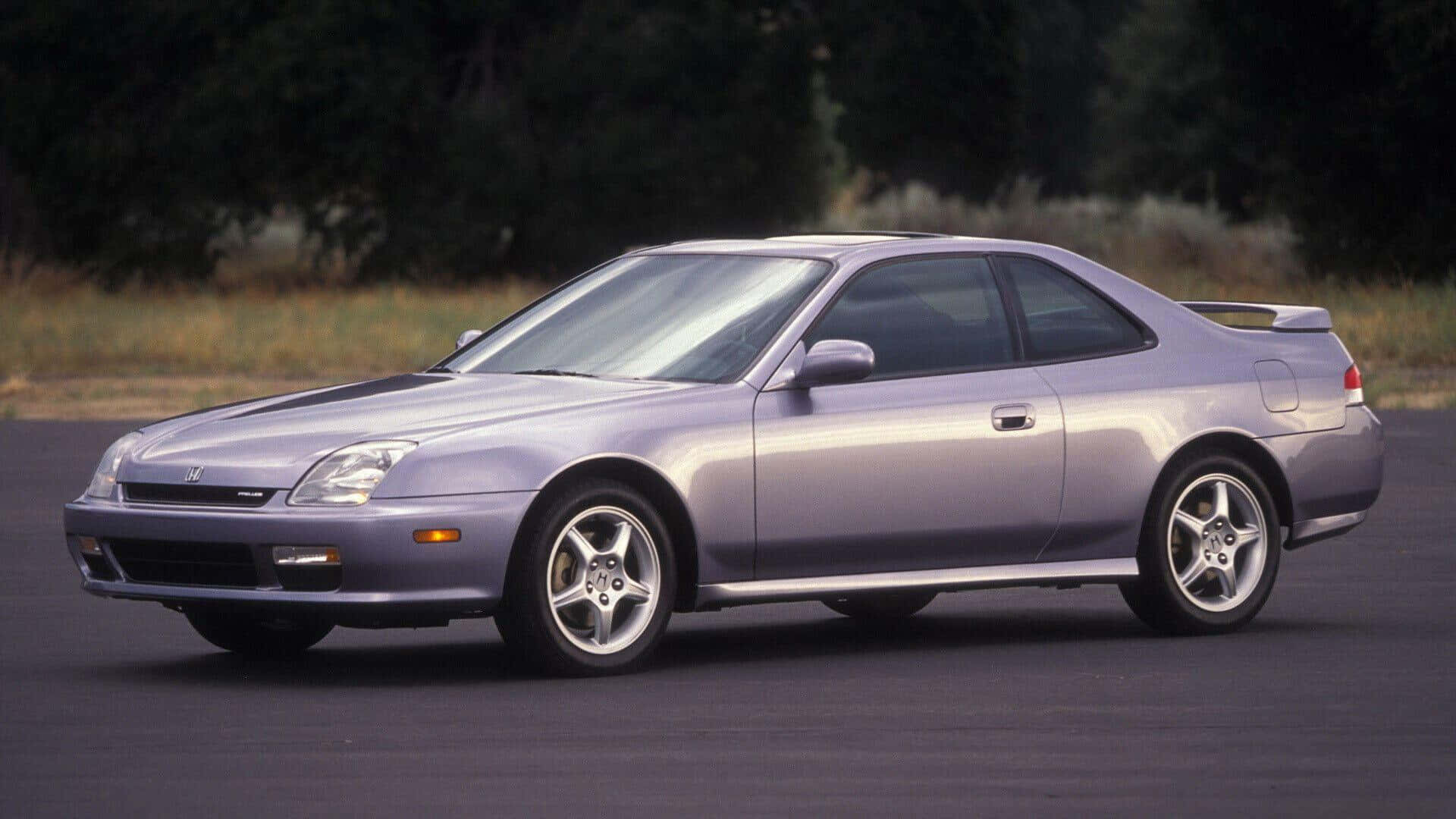 Honda Prelude 桌布 壁紙 — 一架時尚的銀色運動轎跑車停在瀝青路上，背景有樹木和乾草。