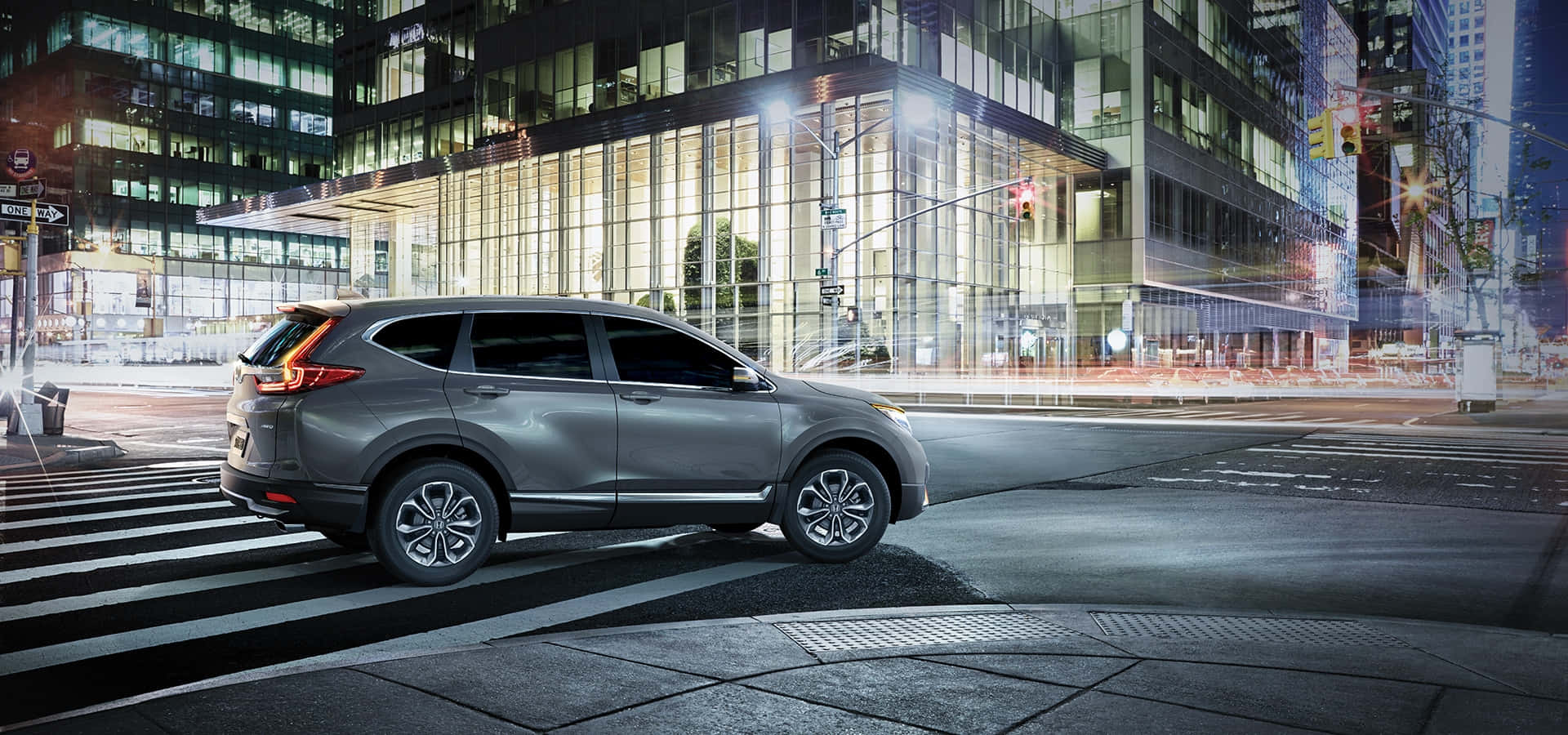 Honda Cr-v 桌布 壁紙 — 一輛時尚的銀色SUV在夜間停泊於城市行人過路處，周圍是閃爍的霓虹燈和高聳的玻璃建築。